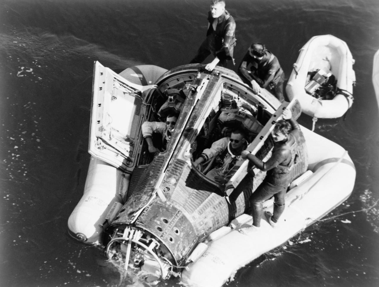 S66-18602_alt (16 March 1966) --- Astronauts Neil A. Armstrong and David R. Scott sit with their spacecraft hatches open while awaiting the arrival of the recovery ship, the USS Leonard F. Mason after the successful completion of their Gemini-8 mission. They are assisted by U.S. Navy divers. The overhead view shows the Gemini-8 spacecraft with the yellow flotation collar attached to stabilize the spacecraft in choppy seas. The green marker dye is highly visible from the air and is used as a locating aid. Photo credit: NASA