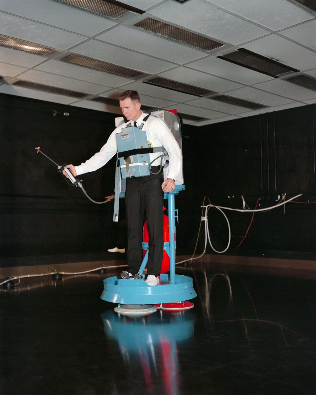 S66-19284 (1 Feb. 1966) --- Astronaut David R. Scott practicing for Gemini-8 extravehicular activity (EVA) in building 4 of the Manned Spacecraft Center on the air bearing floor. He is wearing the Hand-Held Maneuvering Unit which he will use during the EVA. Photo credit: NASA