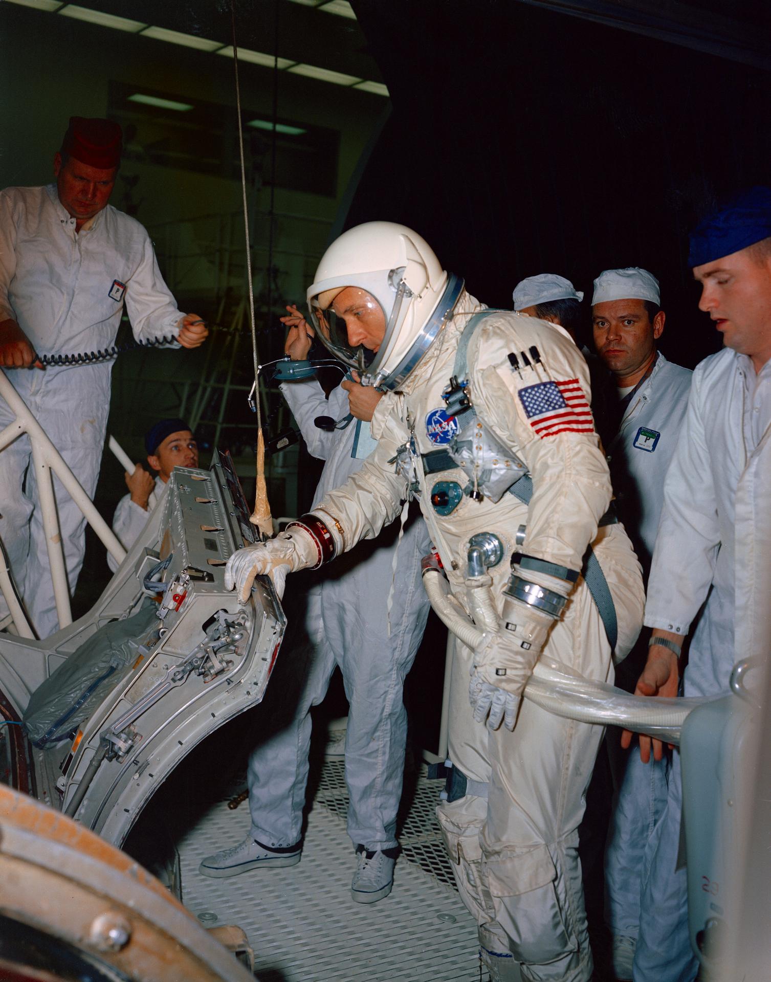 Tom Stafford, suited up, leans in to inspect the Gemini-9 spacecraft