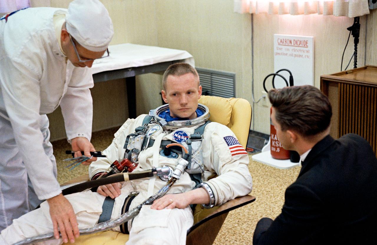 S66-24446 (16 March 1966) --- Astronaut Neil A. Armstrong, command pilot of the Gemini-8 spaceflight, sits in the Launch Complex 16 trailer during suiting up operations for the Gemini-8 mission. Suit technician Jim Garrepy assists. Photo credit: NASA
