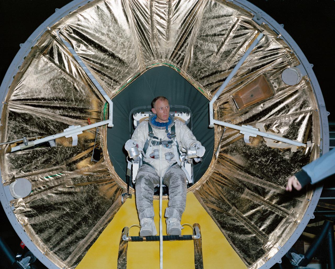 S66-28108 (April 1966) --- Astronaut Edwin E. Aldrin Jr., backup crew pilot of the National Aeronautics and Space Administration's Gemini-9 spaceflight, practices donning the Astronaut Maneuvering Unit (AMU) backpack in Building 5. An AMU will be used by astronaut Eugene A. Cernan, prime crew pilot, during Gemini-9 extravehicular activity (EVA). Photo credit: NASA