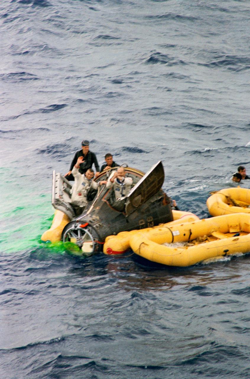 S66-34110 (6 June 1966) --- Astronauts Thomas Stafford (right) and Eugene Cernan wave to those aboard the aircraft carrier USS Wasp as the recovery ship approaches. U.S. Navy frogmen assist in the recovery operations. Gemini-9A splashed down in the Atlantic Ocean only 3.5 miles from the USS Wasp. Gemini-9 splashed down 345 miles east of Cape Kennedy at 9 a.m. (EST), June 6, 1966. Photo credit: NASA