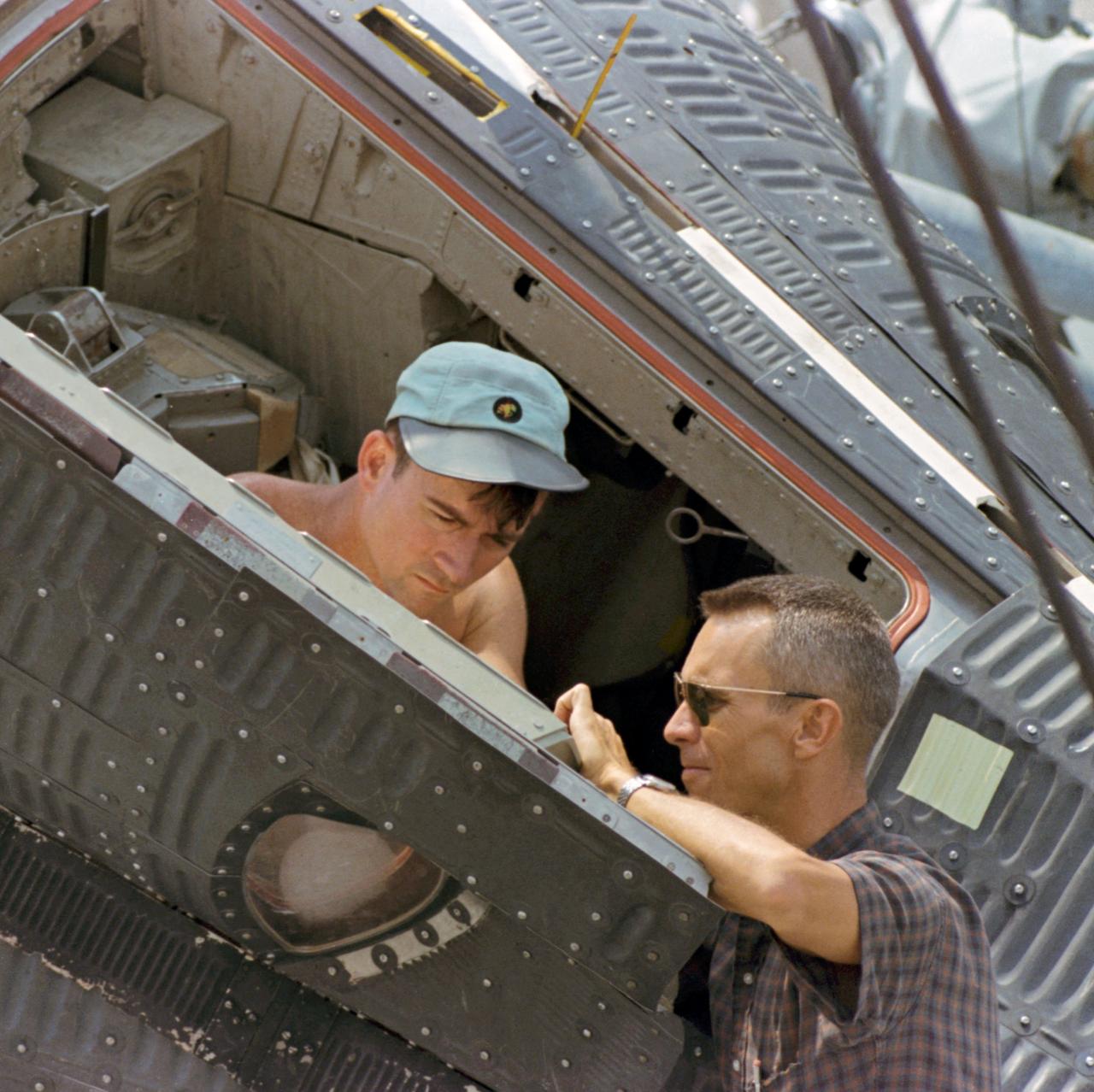 S66-39691 (18 June 1966) --- Astronaut John W. Young, prime crew command pilot for the Gemini-10 spaceflight, sits in Static Article 5 during water egress training activity onboard the NASA Motor Vessel Retriever. The SA-5 will be placed in the water and he and astronaut Michael Collins will then practice egress and water survival techniques. At right is Gordon Harvey, Spacecraft Operations Branch, Flight Crew Support Division. Photo credit: NASA