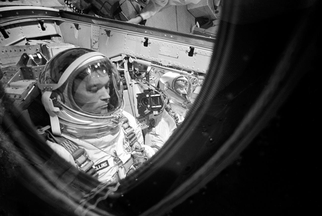 S66-46477 (18 July 1966) --- Close-up of astronaut Michael Collins, Gemini-10 pilot, making final adjustments and checks in the Gemini spacecraft during prelaunch countdown. In right background is astronaut John W. Young, command pilot. Photo credit: NASA