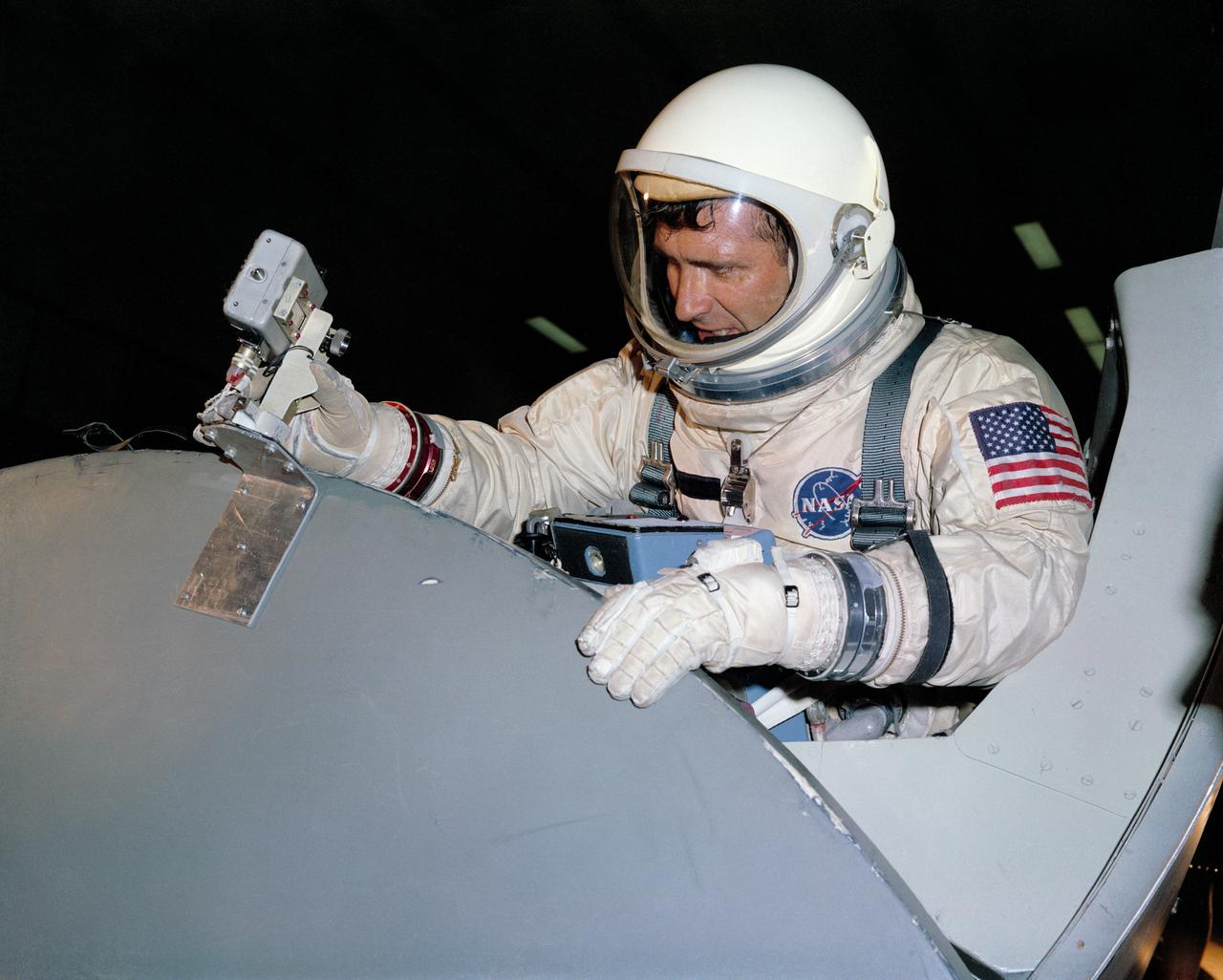 S66-50179 (10 Aug. 1966) --- Astronaut Richard F. Gordon Jr., prime crew pilot for the Gemini-11 spaceflight, practices attaching to a Gemini boilerplate a camera which will film his extravehicular activity (EVA) outside the spacecraft. The training exercise is being conducted in the Astronaut Training Building, Kennedy Space Center, Florida. Photo credit: NASA