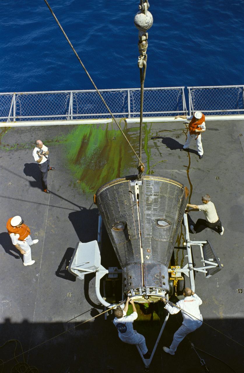 S66-50743 (15 Sept. 1966) --- The Gemini-11 spacecraft is lowered onto a dolly on the deck of the USS Guam, prime recovery vessel for the Gemini-11 mission. Astronaut Charles Conrad Jr. and Richard F. Gordon Jr. had already been picked up by helicopter from the splashdown area and brought aboard the Guam. Photo credit: NASA