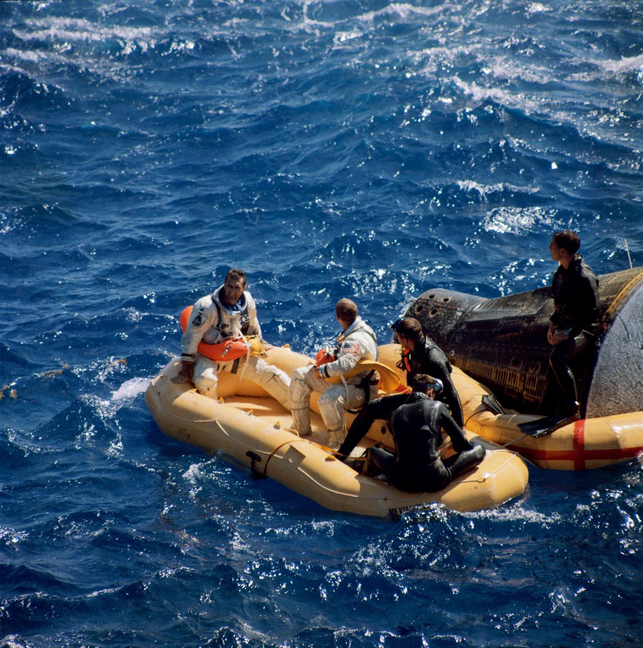 S66-50761 (15 Sept. 1966) --- Astronauts Richard F. Gordon Jr. (left), pilot of the Gemini-11 spaceflight, and Charles Conrad Jr., command pilot, sit in life raft while awaiting pickup by a helicopter from the USS Guam. Members of the Navy frogman team wait with them. Photo credit: NASA