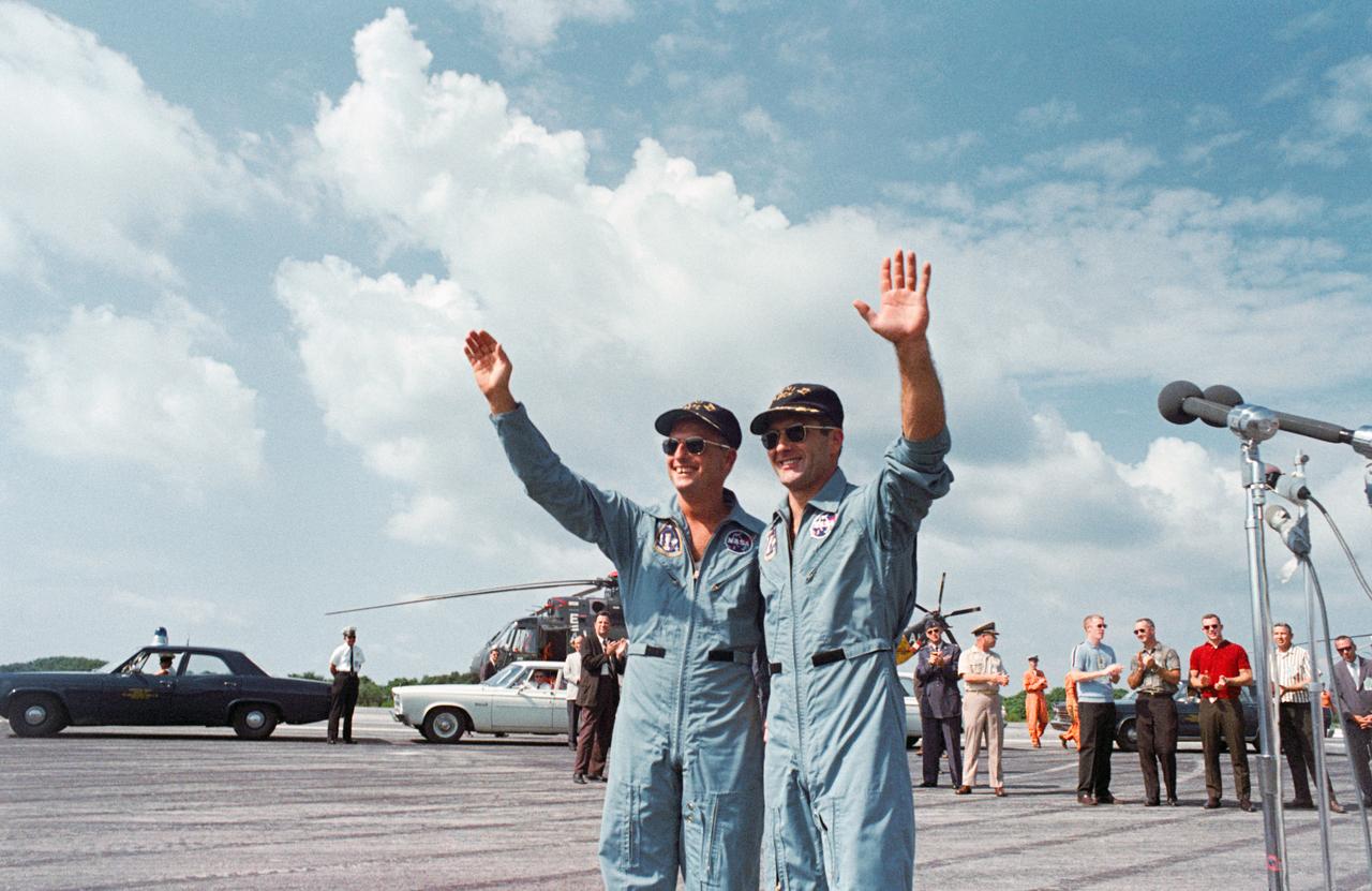 S66-50763 (16 Sept. 1966) --- Astronauts Charles Conrad Jr. (left), command pilot, and Richard F. Gordon Jr., pilot, wave to the welcome crowd at the Cape Kennedy skid strip. The Gemini-11 crew had just arrived by helicopter from the recovery ship, USS Guam. Gemini-11 splashed down in the western Atlantic, 700 miles east of Cape Kennedy, at 9 a.m. (EST), Sept. 15, 1966 to conclude a three-day mission in space. Photo credit: NASA