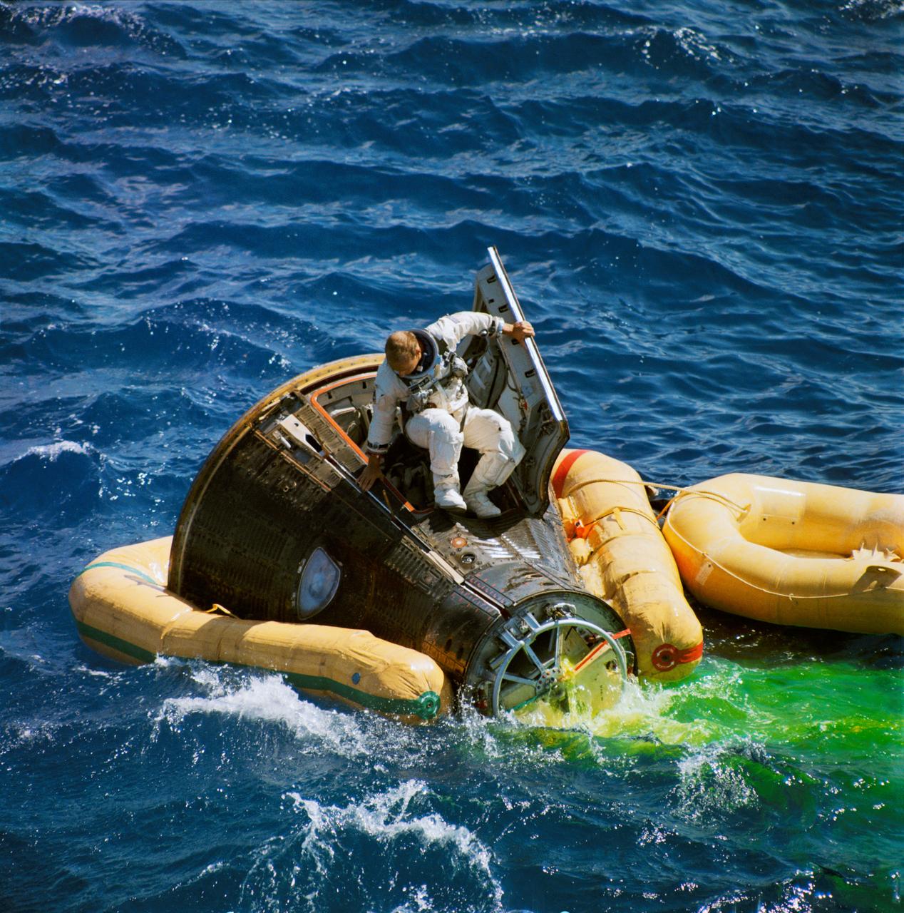 S66-50767 (15 Sept. 1966) --- Astronaut Charles Conrad Jr., command pilot of the Gemini-11 spaceflight, climbs from the spacecraft minutes after splashdown. Astronaut Richard F. Gordon Jr., pilot, still has his hatch closed. A U.S. Navy frogman team attached a flotation collar to the spacecraft. A recovery helicopter from the USS Guam picked up the two astronauts. Photo credit: NASA