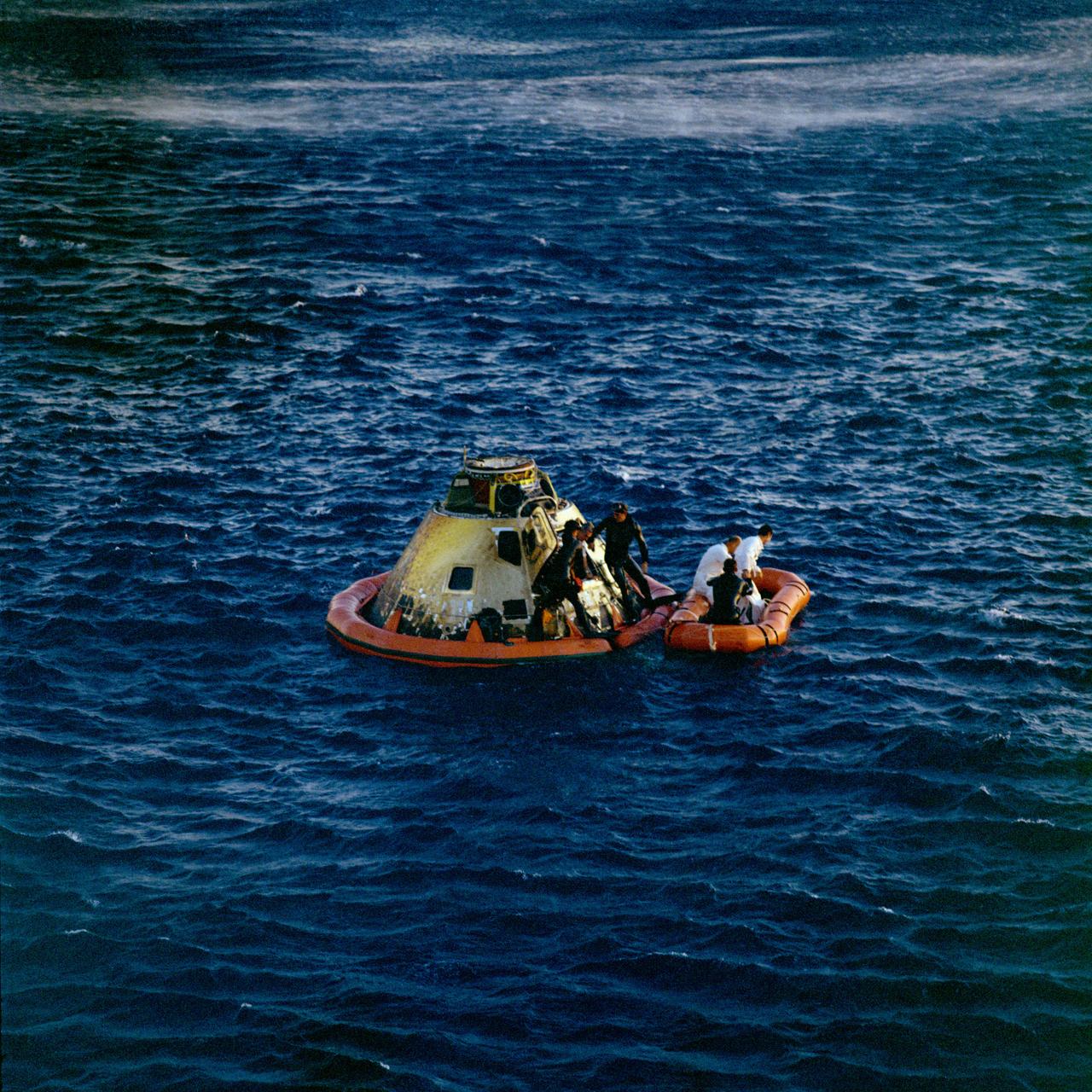 S69-20638 (26 May 1969) --- Astronaut Eugene A. Cernan, lunar module pilot, egresses the Apollo 10 spacecraft during recovery operations in the South Pacific. U.S. Navy underwater demolition team swimmers assist in the recovery operations. Already in life raft are astronauts Thomas P. Stafford (left), commander; and John W. Young, command module pilot. The three crewmen were picked up by helicopter and flown to the prime recovery ship, USS Princeton. Splashdown occurred at 11:53 a.m. (CDT), May 26, 1969, about 400 miles east of American Samoa, and about four miles from the recovery ship, to conclude a successful eight-day lunar orbit mission.