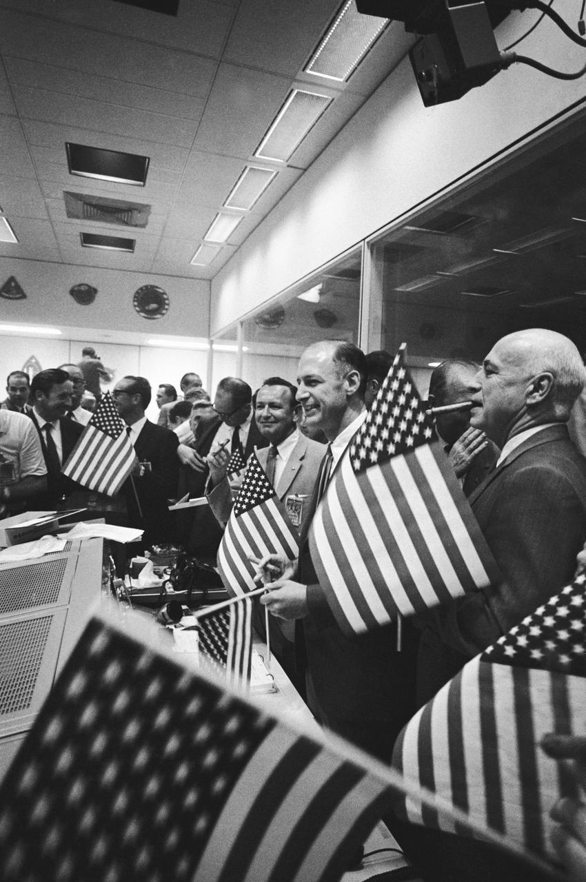 S69-40024 (24 July 1969) --- NASA and Manned Spacecraft Center (MSC) officials join in with the flight controllers, in the Mission Operations Control Room (MOCR) in the Mission Control Center (MCC), in celebrating the successful conclusion of the Apollo 11 lunar landing mission. Identifiable in the picture, starting in foreground, are Dr. Robert R. Gilruth, MSC Director; George M. Low, Manager, Apollo Spacecraft Program, MSC; Dr. Christopher C. Kraft Jr., MSC Director of Flight Operation; U.S. Air Force Lt. Gen. Samuel C. Phillips (with glasses, looking downward), Apollo Program Director, Office of Manned Space Flight, NASA Headquarters; and Dr. George E. Mueller (with glasses, looking toward left), Associate Administrator, Office of Manned Space Flight, NASA Headquarters. Former astronaut John H. Glenn Jr. is standing behind Mr. Low.