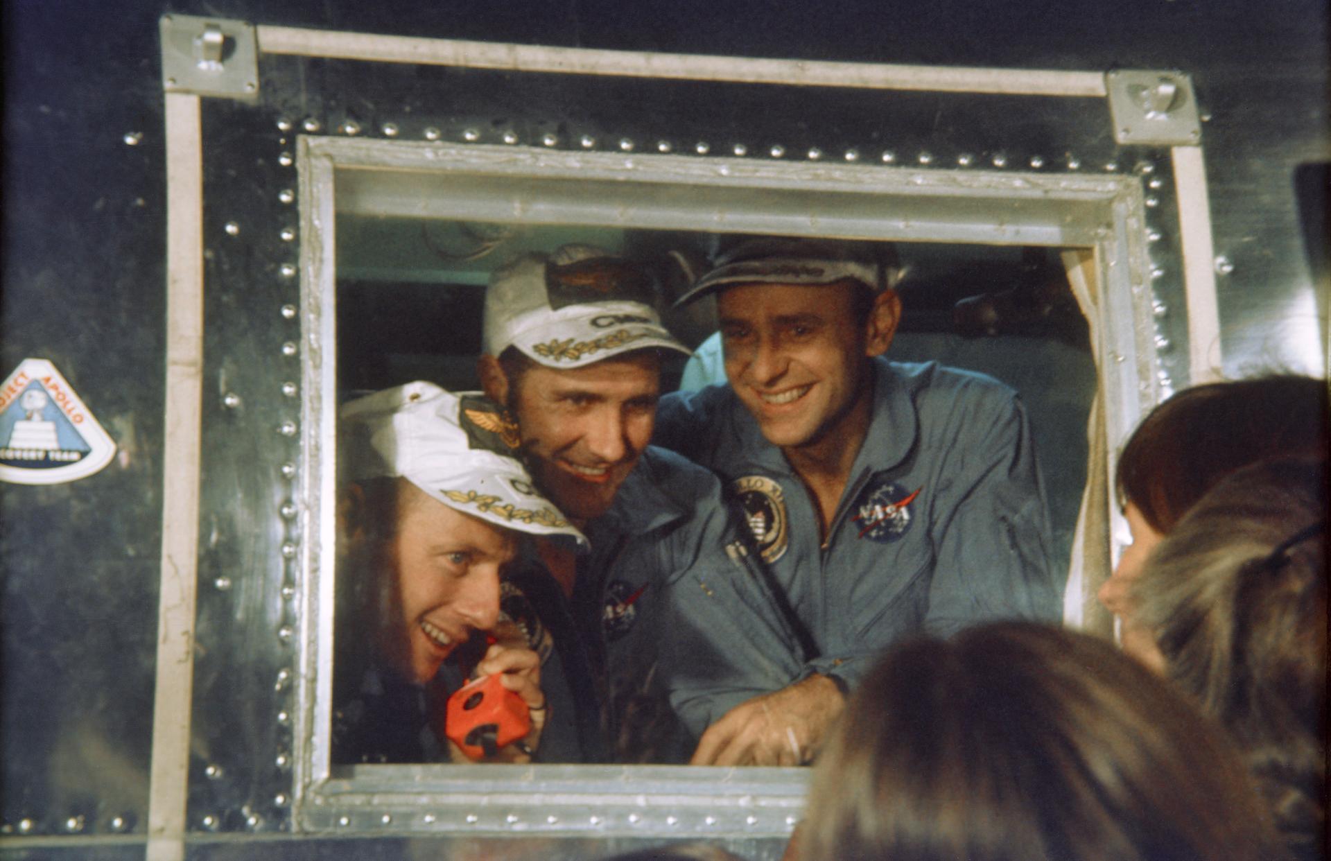 The 3 Apollo 12 astronauts look through the window of the Mobile Quarantine Facility after their return to Earth