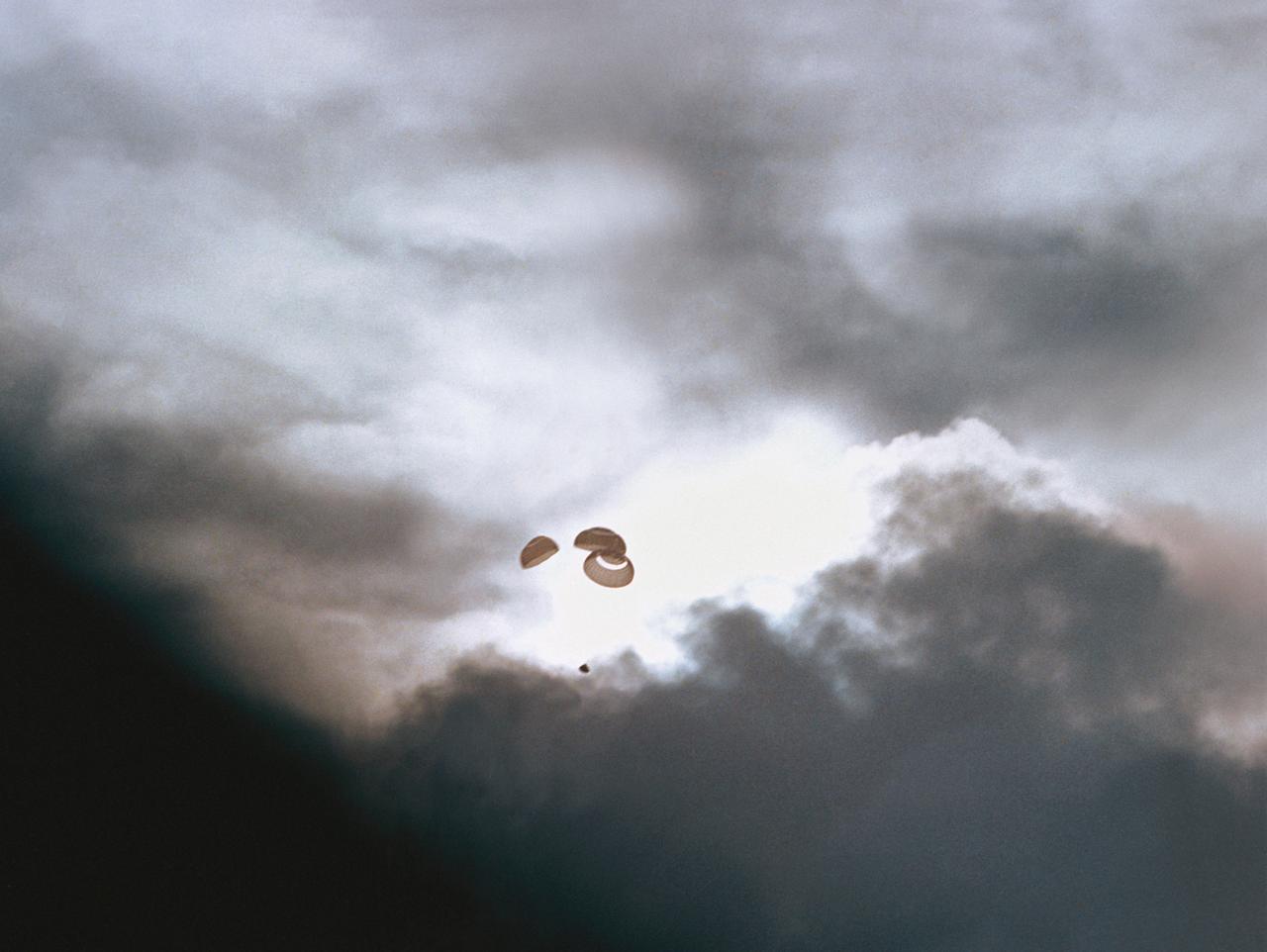 S70-35652 (17 April 1970) --- The Apollo 13 spacecraft heads toward a splashdown in the South Pacific Ocean. The Apollo 13 Command Module splashed down in the South Pacific at 12:07:44 p.m., April 17, 1970. Note the capsule and its parachutes just visible against a gap in the dark clouds.