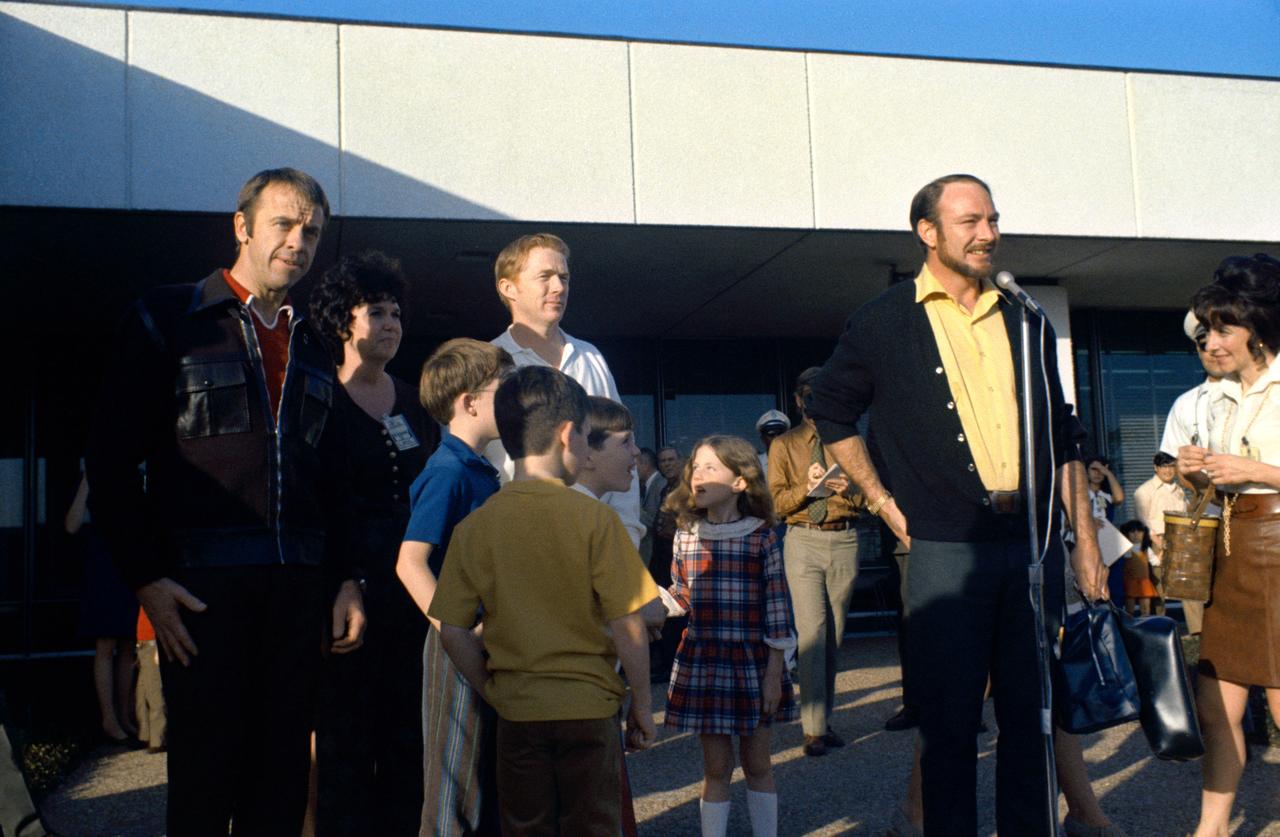 S71-22028 (26 Feb. 1971) --- Astronaut Edgar D. Mitchell, right, the Apollo 14 lunar module pilot, addresses NASA-MSC personnel and news media representatives and other visitors soon after he and his fellow crewmen were released from a 15-day confinement period in the Lunar Receiving Laboratory. Pictured with Mitchell in front of the LRL, MSC Building 37, are astronauts Alan B. Shepard Jr., left, commander; and Stuart A Roosa, command module pilot, Mrs. Mitchell is at right and Mrs. Roosa, near left. Roosa is flanked by his four children, left to right, Christopher A., Stuart A. Roosa Jr., John D. and Rosemary D.
