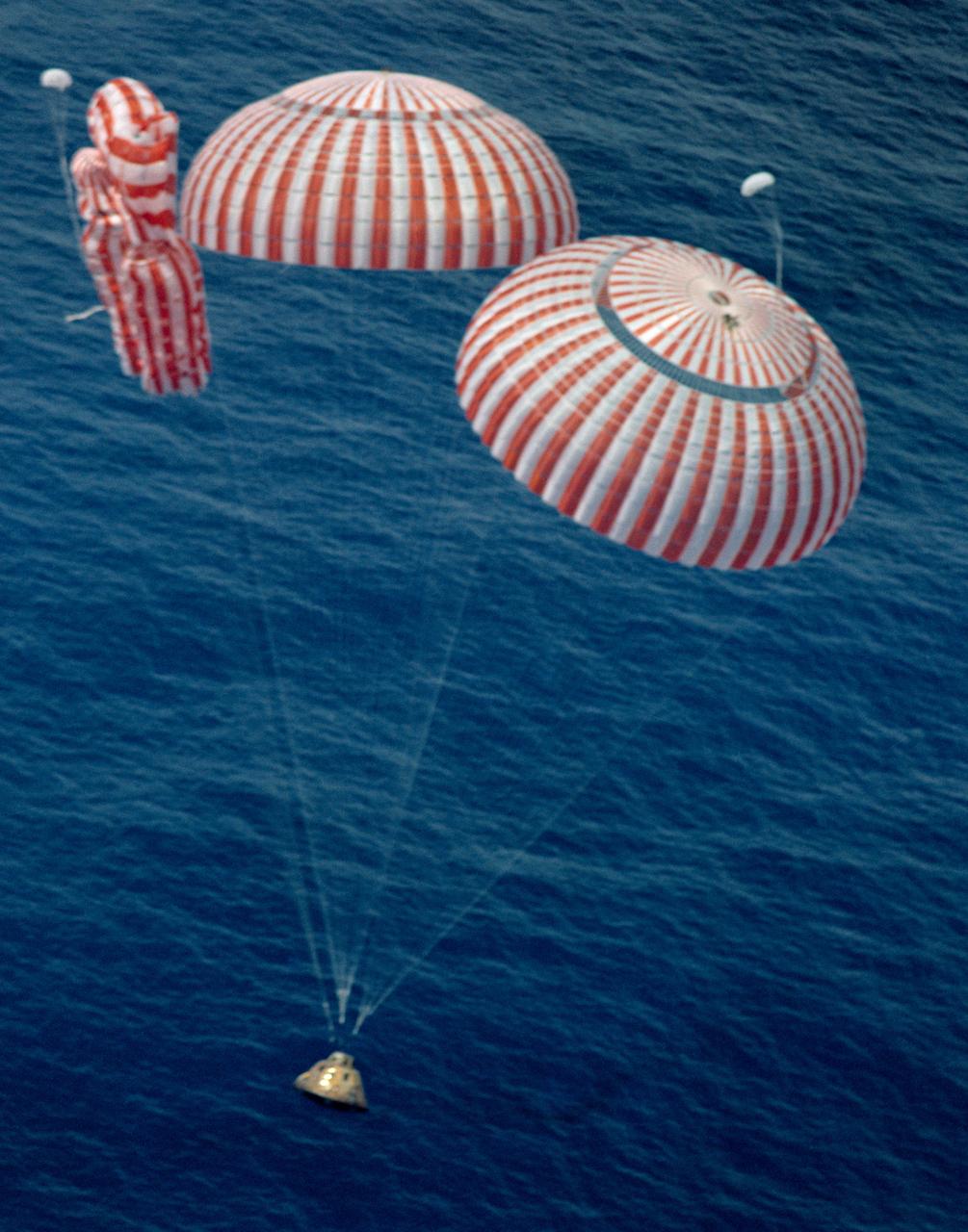 S71-41999 (7 Aug. 1971) --- The Apollo 15 Command Module (CM), with astronauts David R. Scott, commander; Alfred M. Worden, command module pilot; and James B. Irwin, lunar module pilot, aboard, nears a safe touchdown in the mid-Pacific Ocean to conclude a highly successful lunar landing mission. Although causing no harm to the crewmen, one of the three main parachutes failed to function properly. The splashdown occurred at 3:45:53 p.m. (CDT), Aug. 7, 1971, some 330 miles north of Honolulu, Hawaii. The three astronauts were picked up by helicopter and flown to the prime recovery ship USS Okinawa, which was only 6 1/2 miles away.