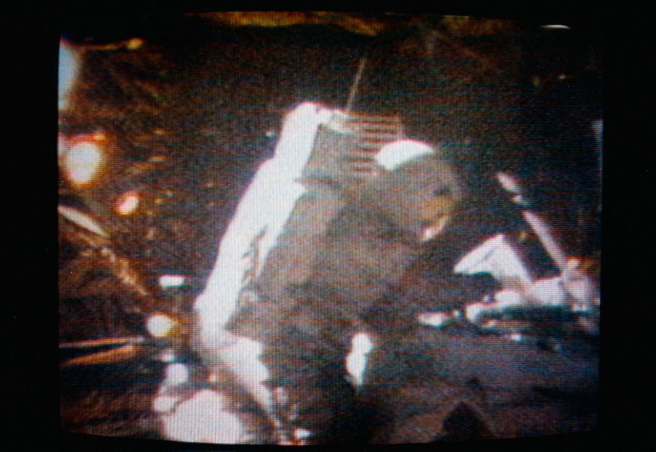 S71-43785 (2 Aug. 1971) --- Astronaut David R. Scott, Apollo 15 commander, performs the act of cancelling the first Apollo 15 commemorative postage stamp on the moon, as seen in this color reproduction taken from a transmission made by the RCA color television camera mounted on the Lunar Roving Vehicle. Scott holds a stamp cancellation device in his right hand. The new commemorative postage stamp heralds: "United States in Space -- A Decade of Achievement." The U.S. Postal Service chose artist Robert McCall of Paradise Valley, Arizona, to design the new U.S. eight-cent stamp. The stamp cancellation occurred toward the end of the third and final lunar surface extravehicular activity by astronauts Scott and James B. Irwin, lunar module pilot.