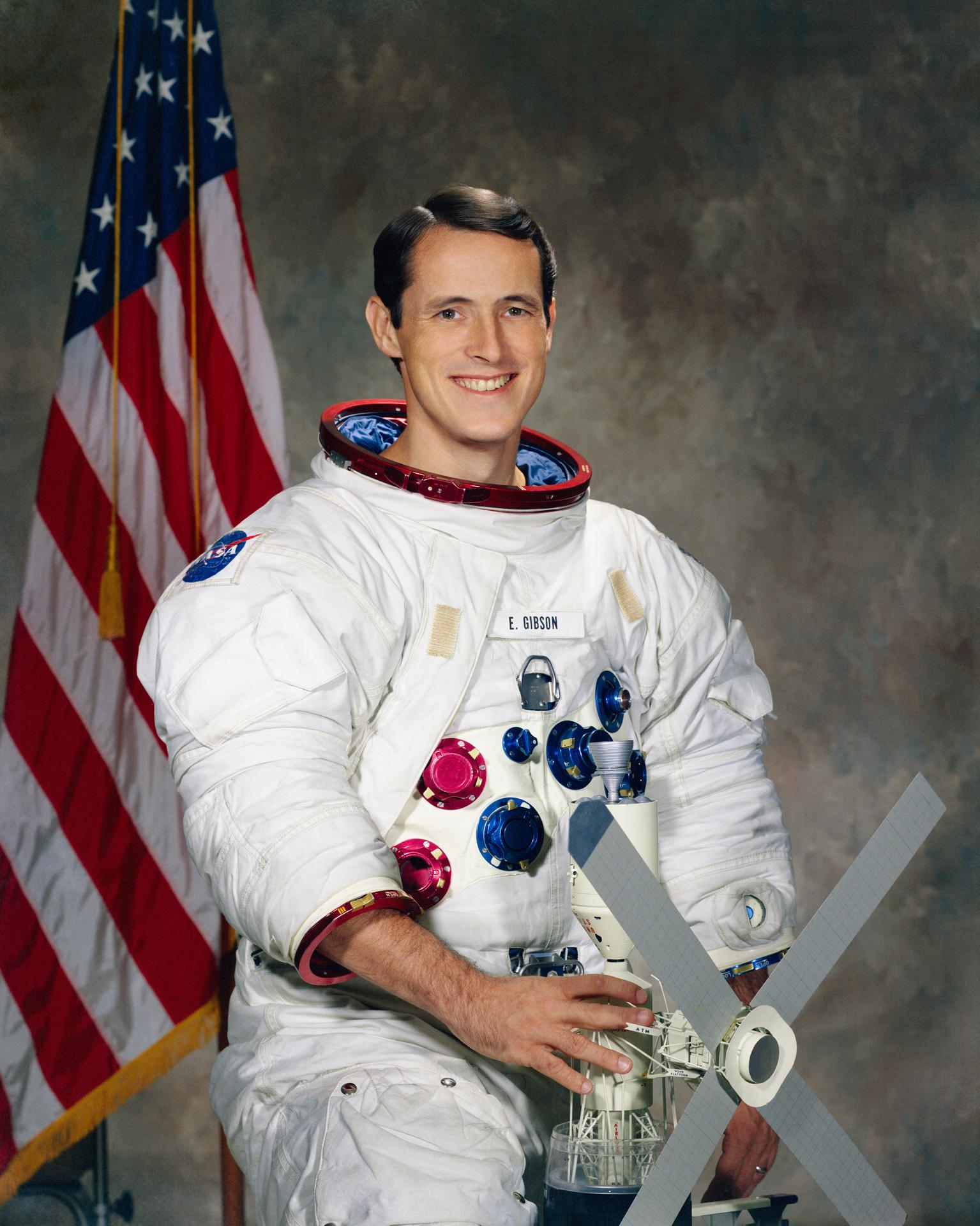 Portrait of Astronaut Edward Gibson holding a model of the Skylab space station