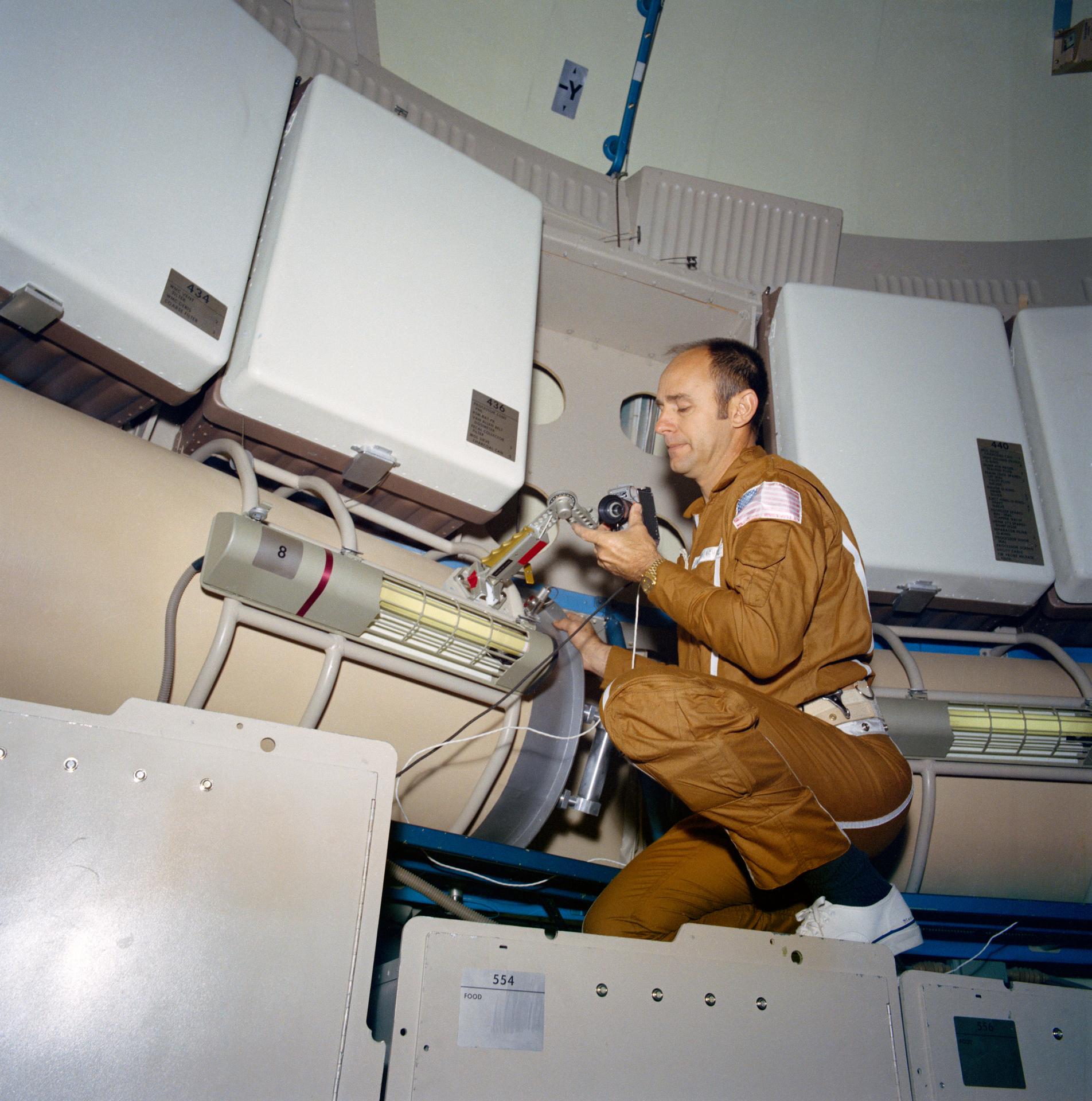 Astronaut Alan Bean holds a data acquisition camera on the Skylab trainer in Houston