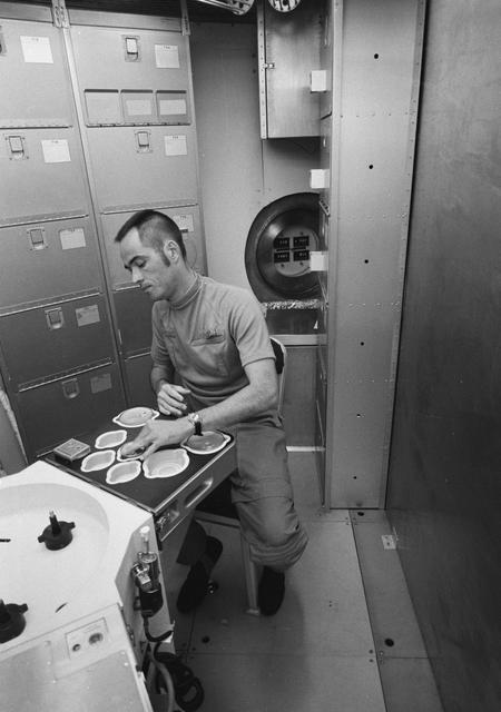 NASA image: Astronaut Robert Crippen simulates preparation of Skylab meal