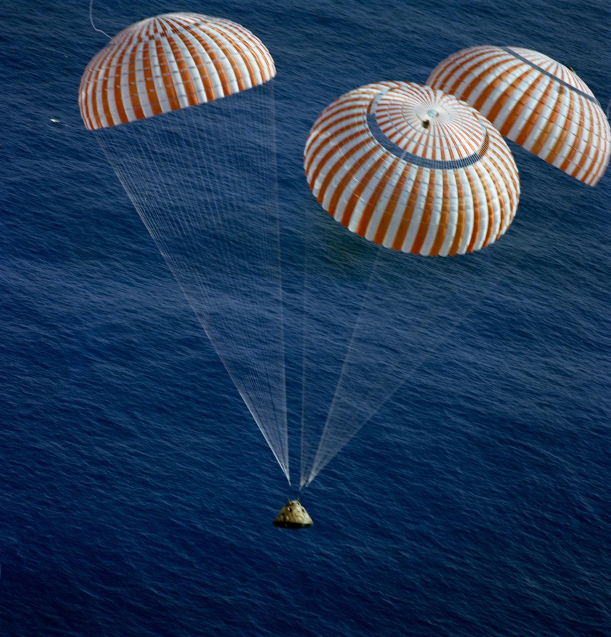 S72-55834 (19 Dec. 1972) --- The Apollo 17 Command Module (CM), with astronauts Eugene A. Cernan, Ronald E. Evans and Harrison H. Schmitt aboard, nears splashdown in the South Pacific Ocean to successfully concludes the final lunar landing mission in NASA's Apollo program. This overhead view was taken from a recovery aircraft seconds before the spacecraft hit the water. The splashdown occurred at 304:31:59 ground elapsed time, 1:24:59 p.m. (CST) Dec. 19, 1972, at coordinates of 166 degrees 8 minutes west longitude and 27 degrees 53 minutes south latitude, about 350 nautical miles southeast of the Samoan Islands. The splashdown was only .8 miles from the target point. Later, the three crewmen were picked up by a helicopter from the prime recovery ship, USS Ticonderoga.