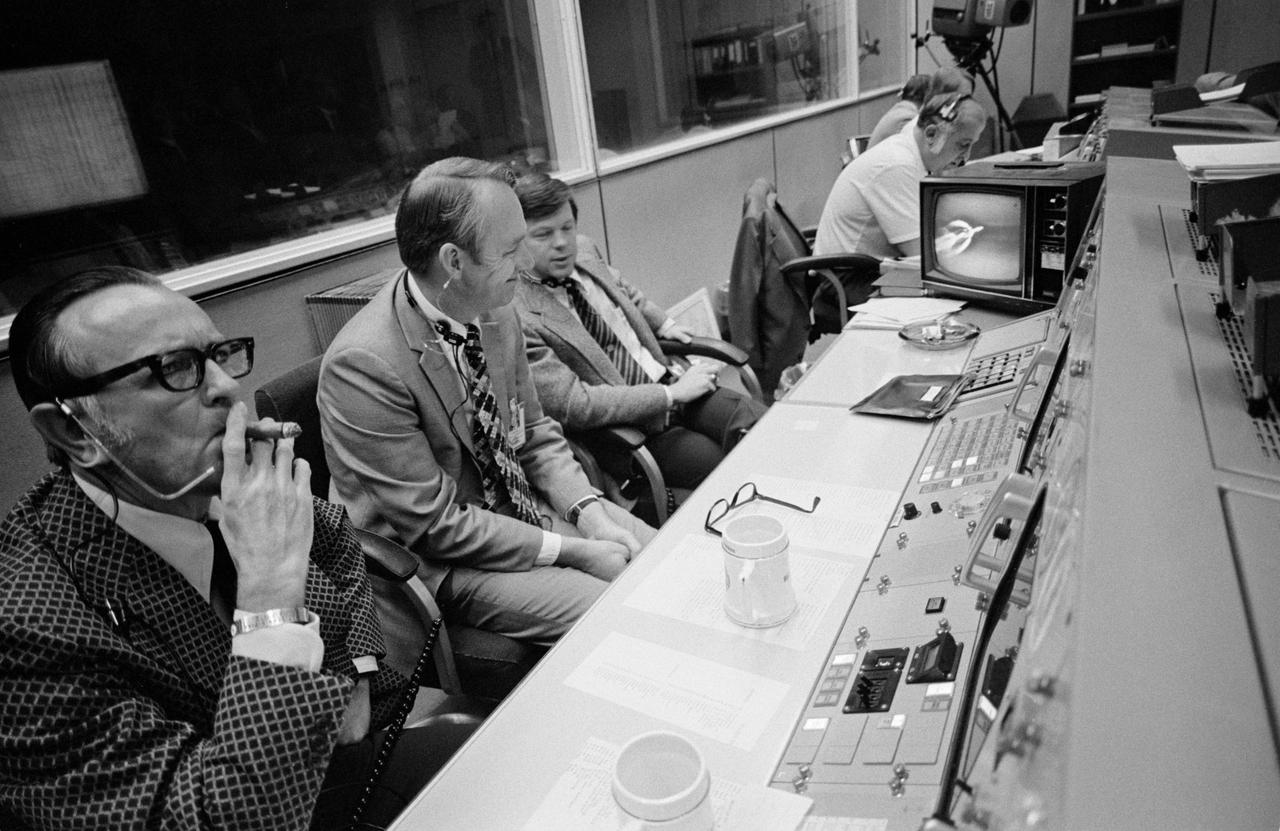 S73-36909 (16 Nov. 2013) --- An overall view of the Flight Operations Director's console in the Mission Operations Control Room in the Mission Control Center at Johnson Space Center during the launch of the Skylab 4 mission. The television monitor records the progress of the flight seconds after liftoff. Left to right, are Dr. Christopher C. Kraft Jr., JSC Director; Howard W. Tindall Jr., JSC Director of Flight Operations; and Flight Director M.P. Frank. Public Affairs commentator John E. McLeish can be seen at the PAO console in the background. Photo credit: NASA