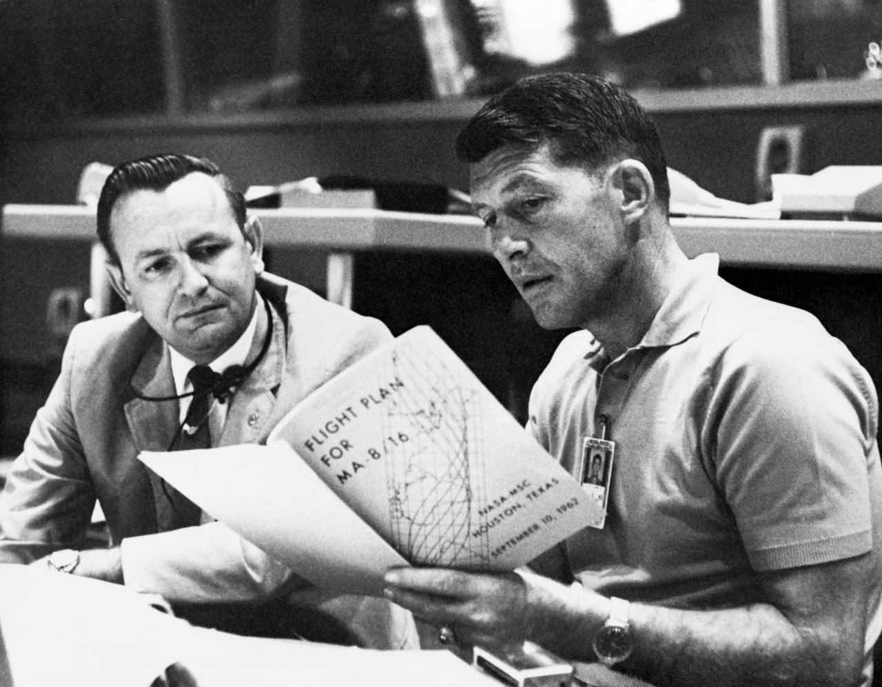 S74-33004 (19 Sept. 1962) --- Astronaut Walter M. Schirra Jr, (right), Mercury-Atlas 8 (MA-8) pilot, discusses the MA-8 flight plan with flight director Christopher C. Kraft Jr., Chief of the Flight Operations Division at the Manned Spacecraft Center, Houston, during MA-8 preflight preparations at Cape Canaveral, Florida. They are seated at a console in the Mercury Control Center. Photo credit: NASA