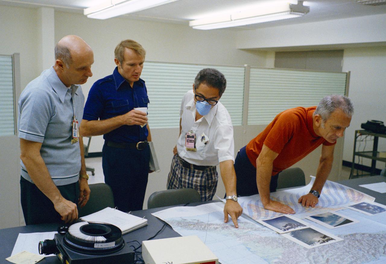 S76-20263 (1975) --- Farouk El-Baz (wearing face mask) is seen with ASTP crewmen T. Stafford, V. Brand and D. Slayton during training activity, Bldg. 5 prior to liftoff in mid-July 1975. They are studying geographic aerial photographs & maps. Photo credit: NASA