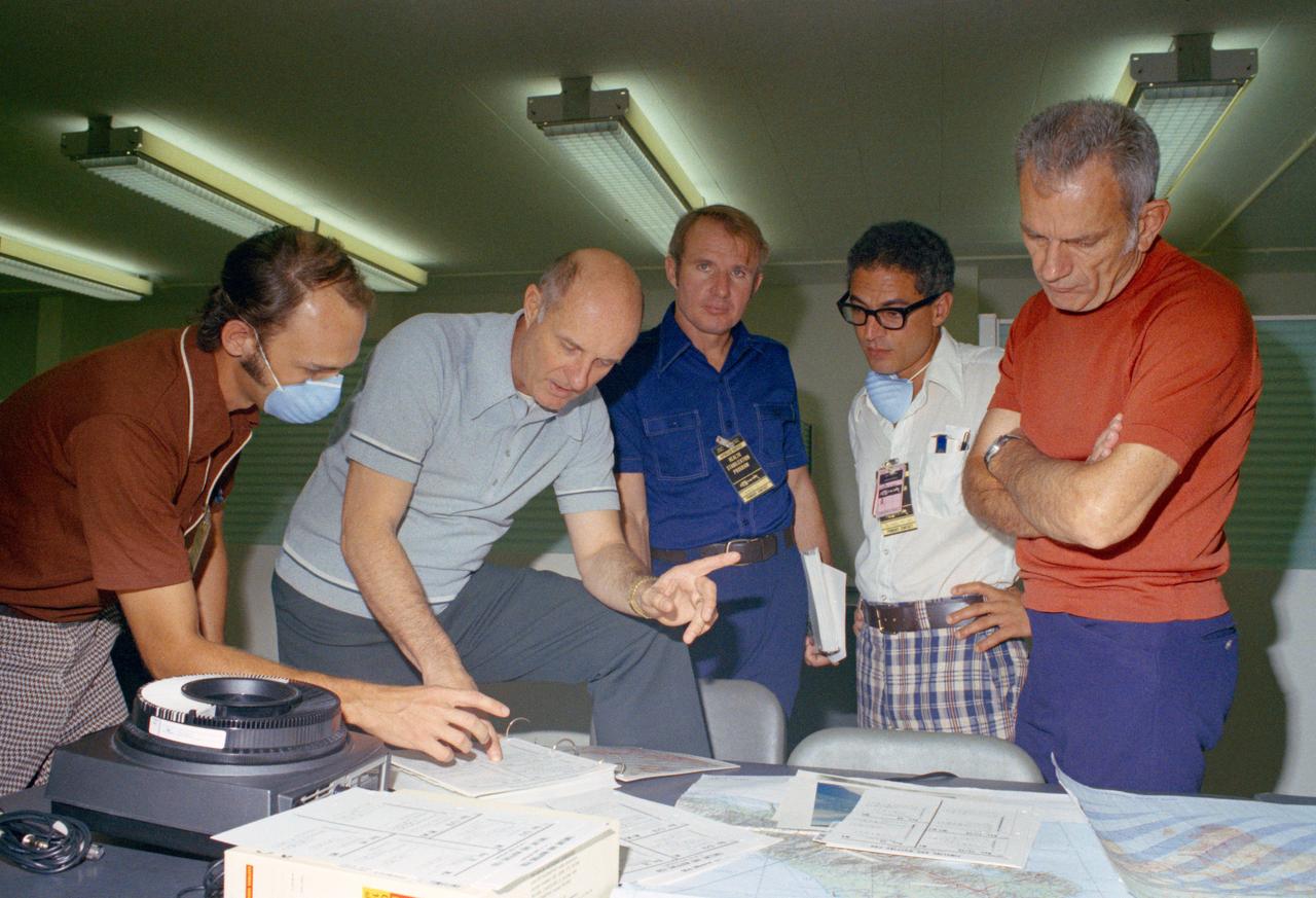 S76-20264 (1975) --- Farouk El-Baz (second right) is seen with ASTP Crewmen T. Stafford, V. Brand and D. Slayton during training activity, Bldg. 5 prior to liftoff in mid-July 1975. They are studying geographic aerial photographs & maps. Photo credit: NASA
