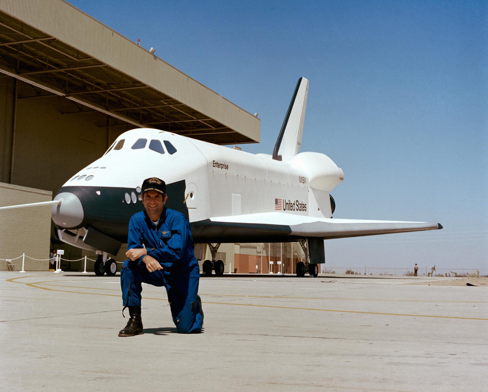 Astronaut Richard H. Truly, kneels in front of the Enterprise Shuttle Orbiter at the Rockwell International Space Division's Orbiter assembly facility at Palmdale, California on the day of the rollout of the Shuttle Orbiter 101 "Enterprise" spacecraft.