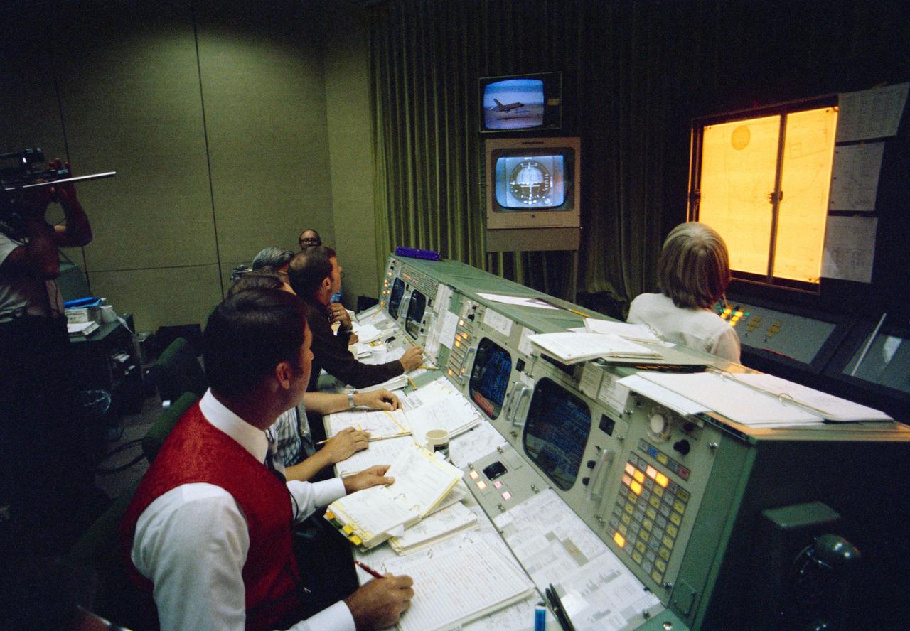 S77-27546 (12 Aug 1977) --- An overall view of Mission Control Operations in the Mission Control Center, bldg 30, at JSC, during the first free flight of the Shuttle Approach and Landing Tests (ALTs) conducted on August 12, 1977 at the Dryden Flight Research Center in Southern California. This view is looking across the console of flight director Donald R. Puddy. The television monitor in the background shows the Orbiter 101 "Enterprise" landing following its five minute 23-second unpowered free flight.