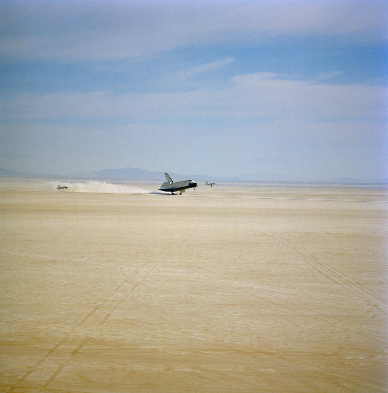 S77-28209 (13 Sept 1977) --- The shuttle orbiter 101 "Enterprise" lands on the desert at Edwards Air Force Base to conclude a five-minute, 31-second unpowered flight during the second free-flight of the Shuttle Approach and Landing Test (ALT) series, on September 13, 1977. Two T-38 chase planes remain with the "Enterprise" for the landing. Asstronauts Joe H. Engle, commander, and Richard H. Truly, pilot, were the crewmen for the flight.