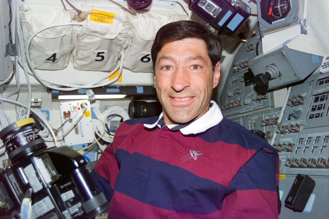 S77-E-5078 (24 May 1996) --- On the Space Shuttle Endeavour's aft flight deck, astronaut Mario Runco, Jr., mission specialist, grabs a hand-held 70mm camera and prepares to take still pictures of an Earth observation target of opportunity.  A pair of windows just out of frame above Runco's head provide the crew members with a prime operating perspective of Earth observation targets.  A crew mate exposed the image with an Electronic Still Camera (ESC).