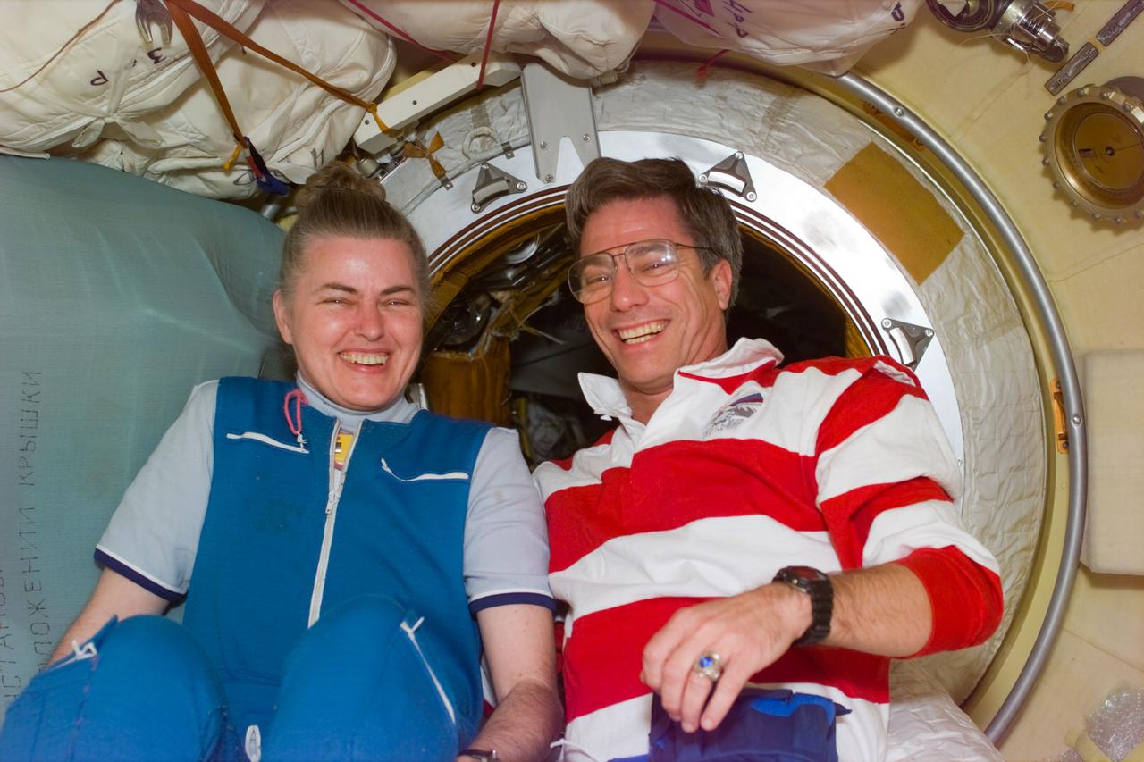 STS79-E-5095 (19 September 1996) --- Soon after Russia's Mir Space Station and the Space Shuttle Atlantis were docked in Earth-orbit, hatchways were quickly and safely opened, making way for special reunions like the one between astronaut and cosmonaut guest researcher Shannon W. Lucid (still attired in her Mir-22 garment) and astronaut John E. Blaha near the tunnel connection to the Docking Module (DM) on Mir, during Flight Day 4.  After spending 180 days aboard Mir, Lucid is with the astronaut who will replace her as cosmonaut guest researcher.  The two have flown together on two previous Space Shuttle missions.