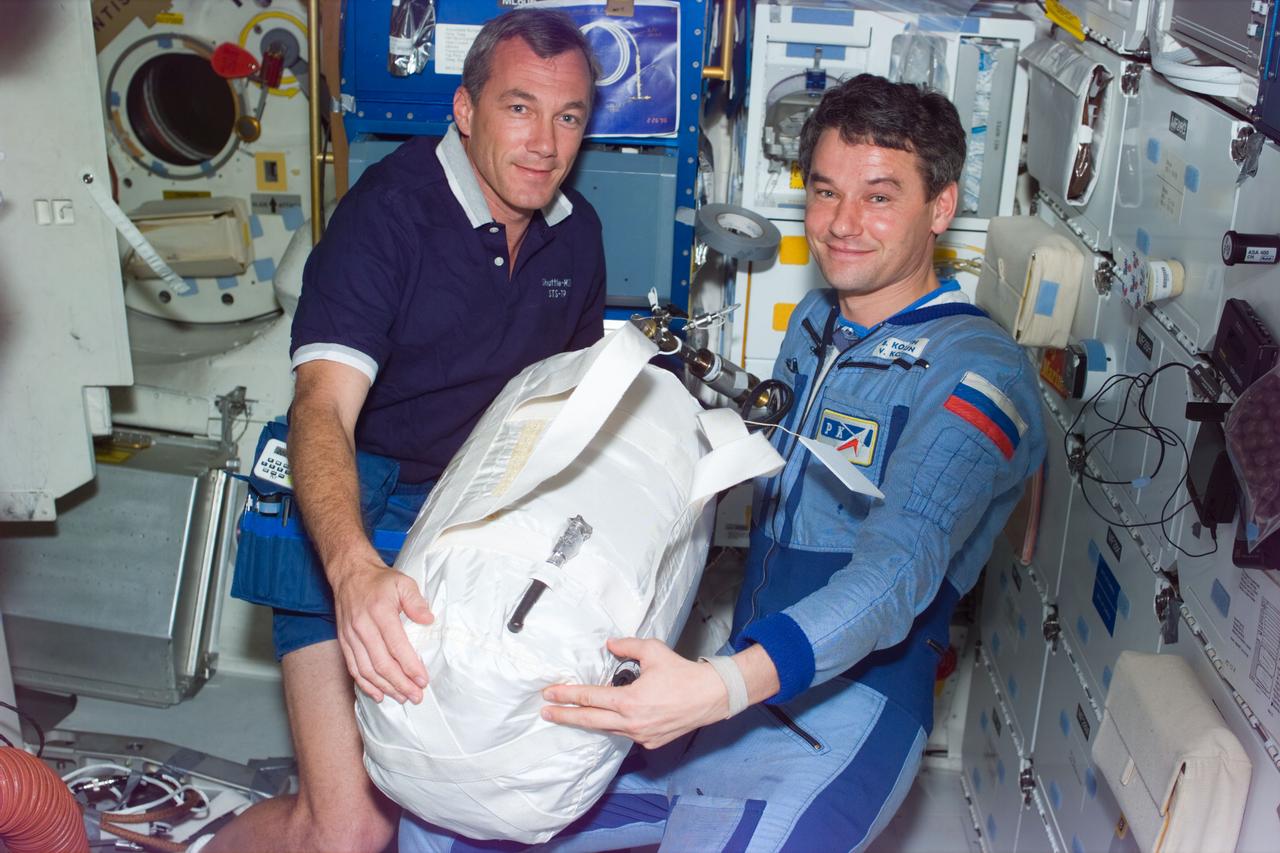 STS79-E-5193 (21 September 1996) --- Astronaut Terrence W. Wilcutt, STS-79 pilot, and cosmonaut Valeri G. Korzun, Mir-22 commander, transfer the Contingency Water Container (CWC), during Flight Day 6.