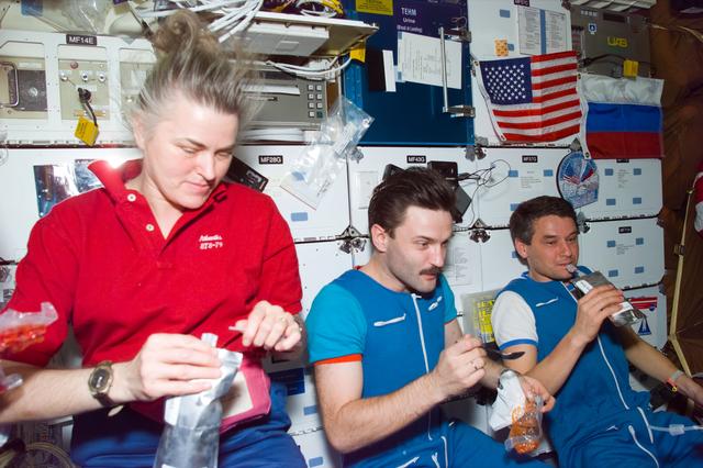 STS-79 and Mir 22 crew share a meal on the Atlantis's middeck