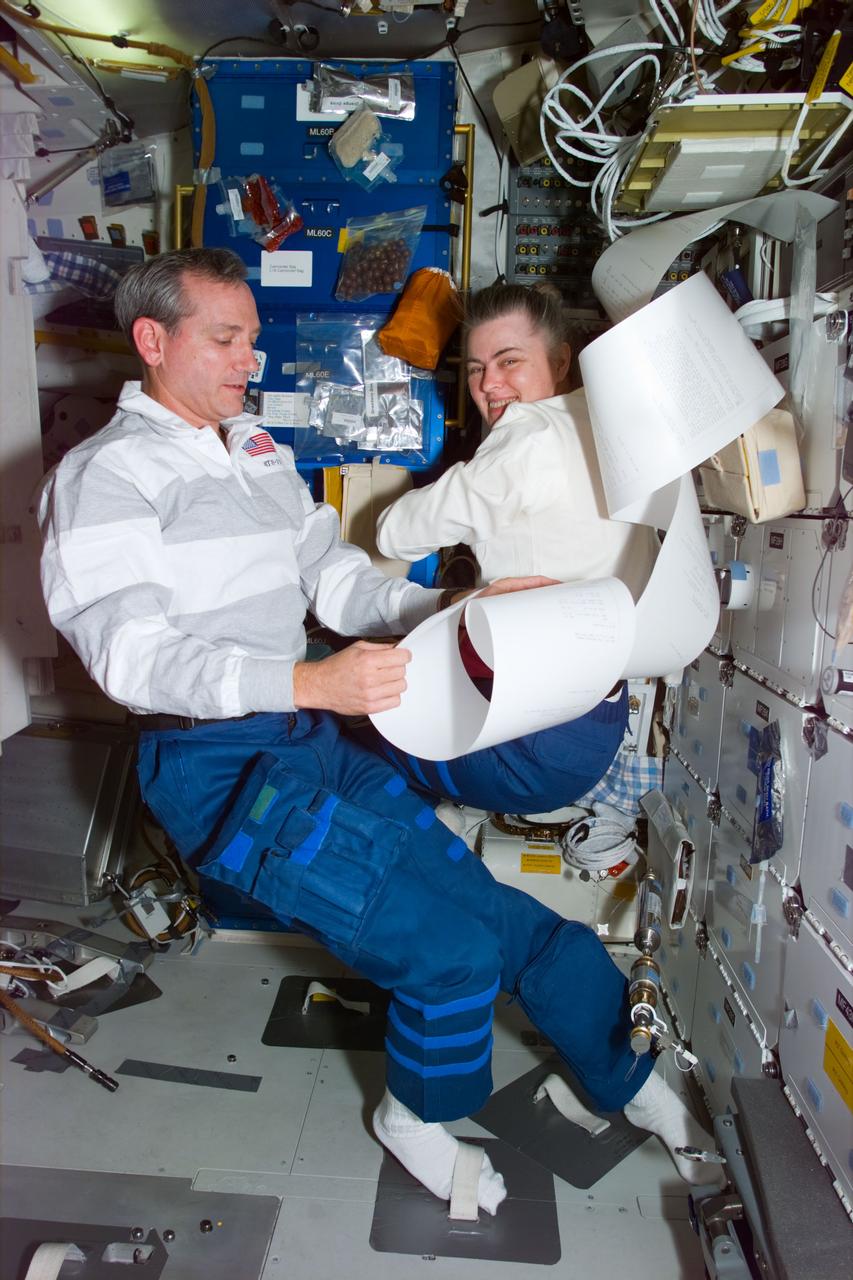 STS79-E-5246 (22 September 1996) --- Astronauts Thomas D. Akers and Shannon W. Lucid check the latest send-up of &quot;mail&quot; on the Space Shuttle Atlantis' mid deck, during Flight Day 7.  The Thermal Imaging Printing System (TIPS) messages likely include information pertinent to the final day of joint activities with the Mir-22 crew members whom Lucid will leave behind for her return to Earth later this week.