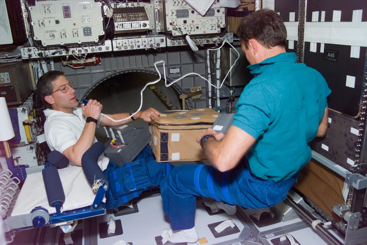 STS79-E-5268 (22 September 1996) --- Astronauts Jerome (Jay) Apt and Thomas D. Akers seal up a transfer stowage bag on the floor at the front end of the Spacehab Module, during Flight Day 7, onboard the Space Shuttle Atlantis.