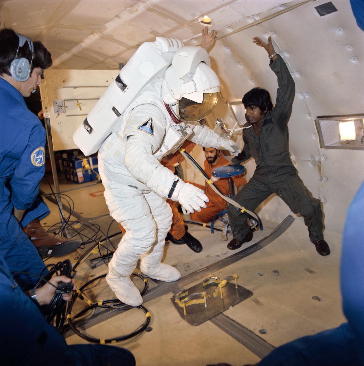 S81-34448 (July 1981) --- Astronaut C. Gordon Fullerton, STS-3 pilot, fully suited, gets a preview of what it might be like in space during a flight aboard NASA's KC-135 "zero-gravity" aircraft. A special parabolic pattern flown the aircraft provides short periods of weightlessness. Fullerton's suit is an Extravehicular Mobility Unit (EMU), used by astronauts when leaving the shirt-sleeve environment of their shuttle orbiter to go outside perform tasks in space. There are no such EVA plans on STS-3, but crew members are trained in this area in the event of the necessity to perform chores in space that for some reason or other can't be done remotely. The astronaut has just donned his suit during a parabola and now takes the opportunity to float around in the absence of gravity. Photo credit: NASA