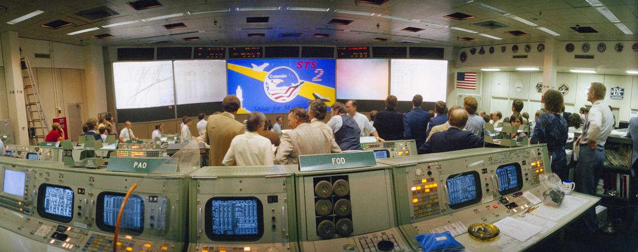 S81-39507 (14 Nov. 1981) --- This unique, wide-angle view of the many flight controllers in Houston?s mission control facility was taken moments prior to the successful touchdown of the STS-2 Columbia. Clifford E. Charlesworth, JSC Deputy Director, huddles with several flight directors for STS-2 at the flight director console on the second-from rear row of consoles in the mission operations control room (MOCR). Eugene F. Kranz, deputy director of flight operations, is at far right of frame. Columbia shortly afterward touched down safely at Edwards Air Force Base in California to complete the two-day, six-hour, 13-minute STS-2 flight. Photo credit: NASA
