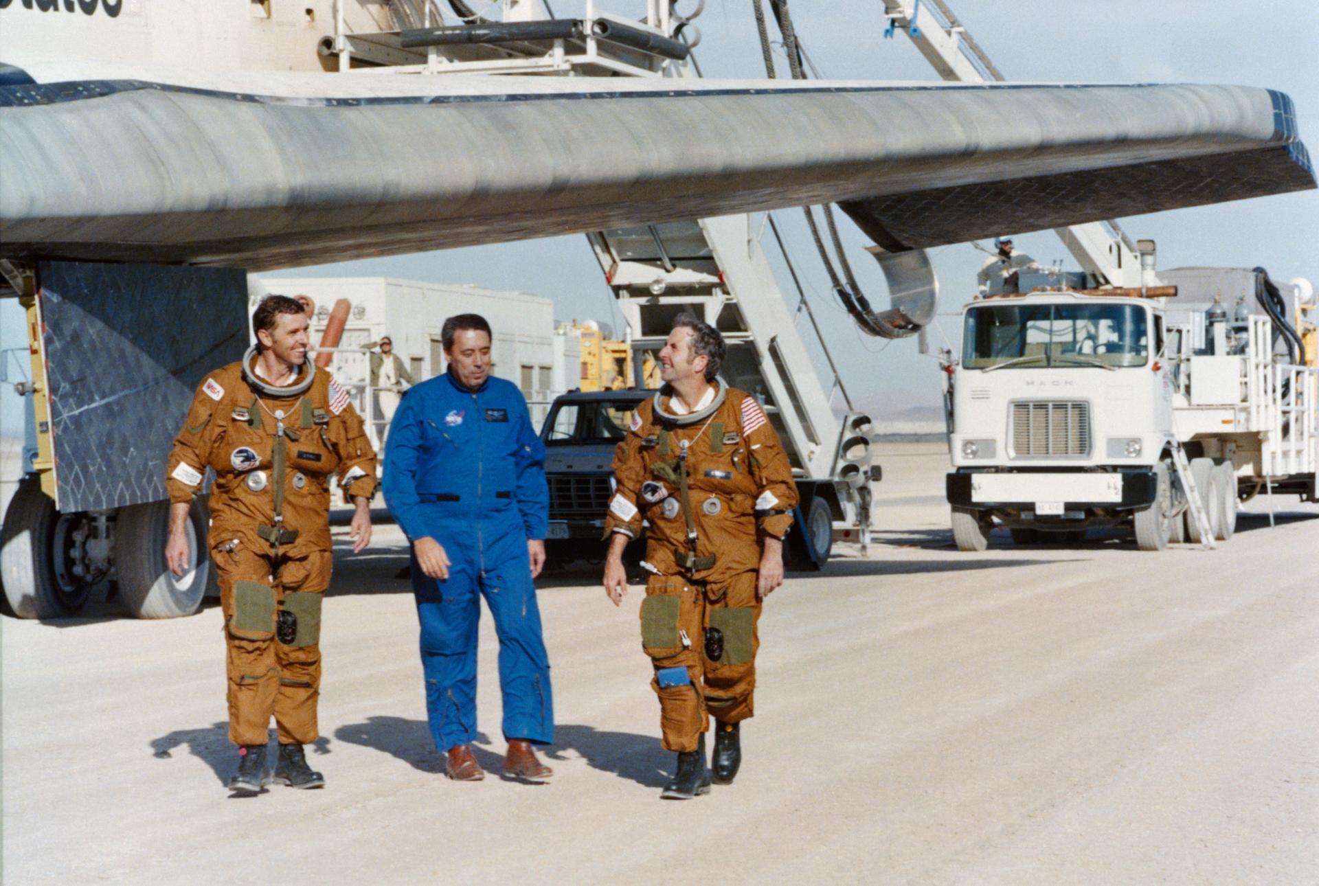 Astronauts Joe H. Engle (left) and Richard H. Truly walk with George W.S. Abbey after landing