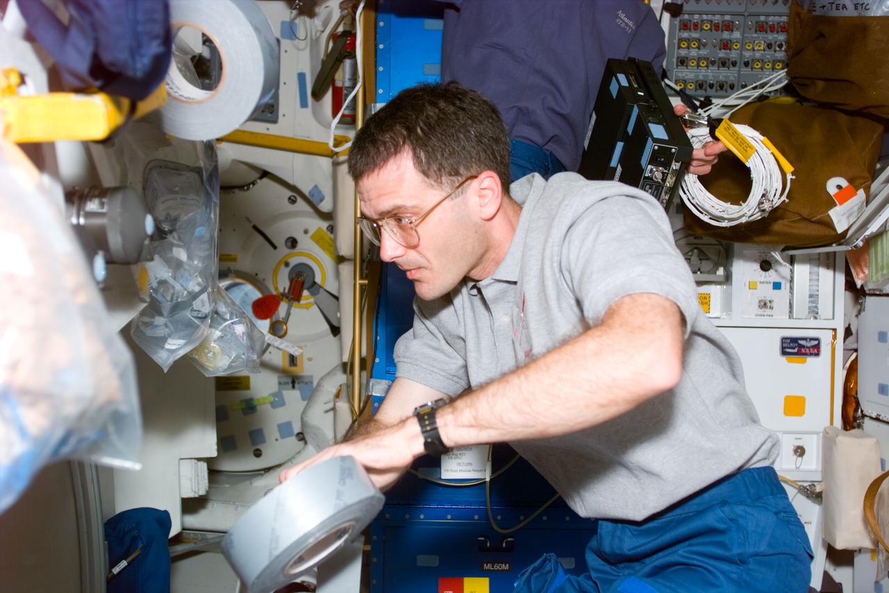 STS081-E-5009 (12 Jan. 1997) --- Astronaut Peter J. K. (Jeff) Wisoff, mission specialist, helps carry out tasks of readying the Space Shuttle Atlantis for almost ten days in space, securing supplies with a piece of gaffer's tape.  Currently, Wisoff is accompanied by five crew mates, among whom one - astronaut Jerry M. Linenger - will be exchanged in a few days for John E. Blaha, who has been aboard Russia's Mir Space Station for several months, as a cosmonaut guest researcher.  Docking of Atlantis with Mir is scheduled for the middle of the week.  The scene was recorded with an Electronic Still Camera (ESC) and later downlinked to flight controllers in Houston, Texas.