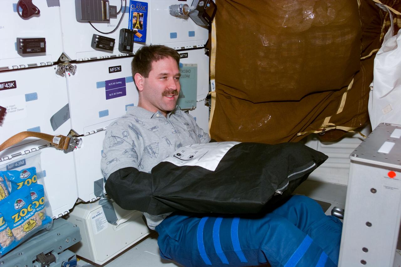 S81-E-05468 (16 Jan. 1997) --- To protect it from exposure to light, astronaut John M. Grunsfeld, mission specialist, uses a black bag to change out a film magazine on a 70mm handheld camera during mid-week activity aboard the Space Shuttle Atlantis. The photograph was recorded with an Electronic Still Camera (ESC) and later was downlinked to flight controllers in Houston, Texas.