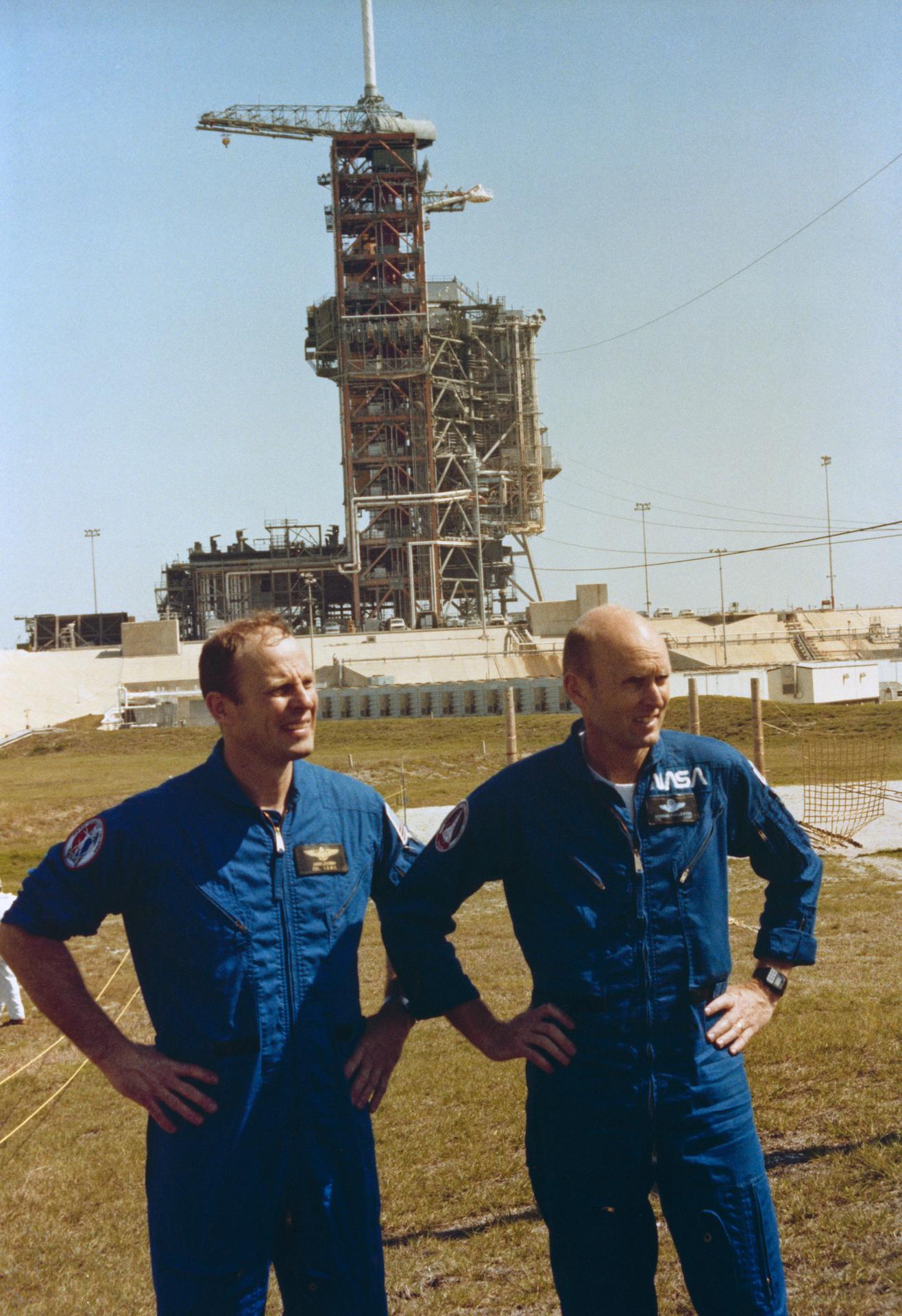 Jack Lousma and Gordon Fullerton pose together in front of launch pad 39A at Kennedy Space Center