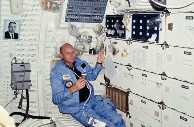 NASA image: Pilot Fullerton plans menu as packaged food and beverages float around him