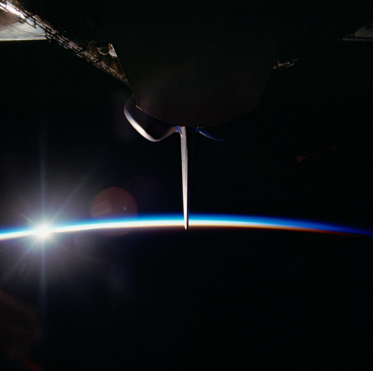 S82-39796 (11-16 Nov. 1982) --- A ?night? scene of the STS-5 space shuttle Columbia in orbit over Earth?s glowing horizon was captured by an astronaut crew member aiming a 70mm handheld camera through the aft windows of the flight deck. The aft section of the cargo bay contains two closed protective shields for satellites which were deployed on the flight. The nearest ?cradle? or shield houses the Satellite Business System?s (SBS-3) spacecraft and is visible in this frame while the Telesta Canada ANIK C-3 shield is out of view. The vertical stabilizer, illuminated by the sun, is flanked by two orbital maneuvering system (OMS) pods. Photo credit: NASA