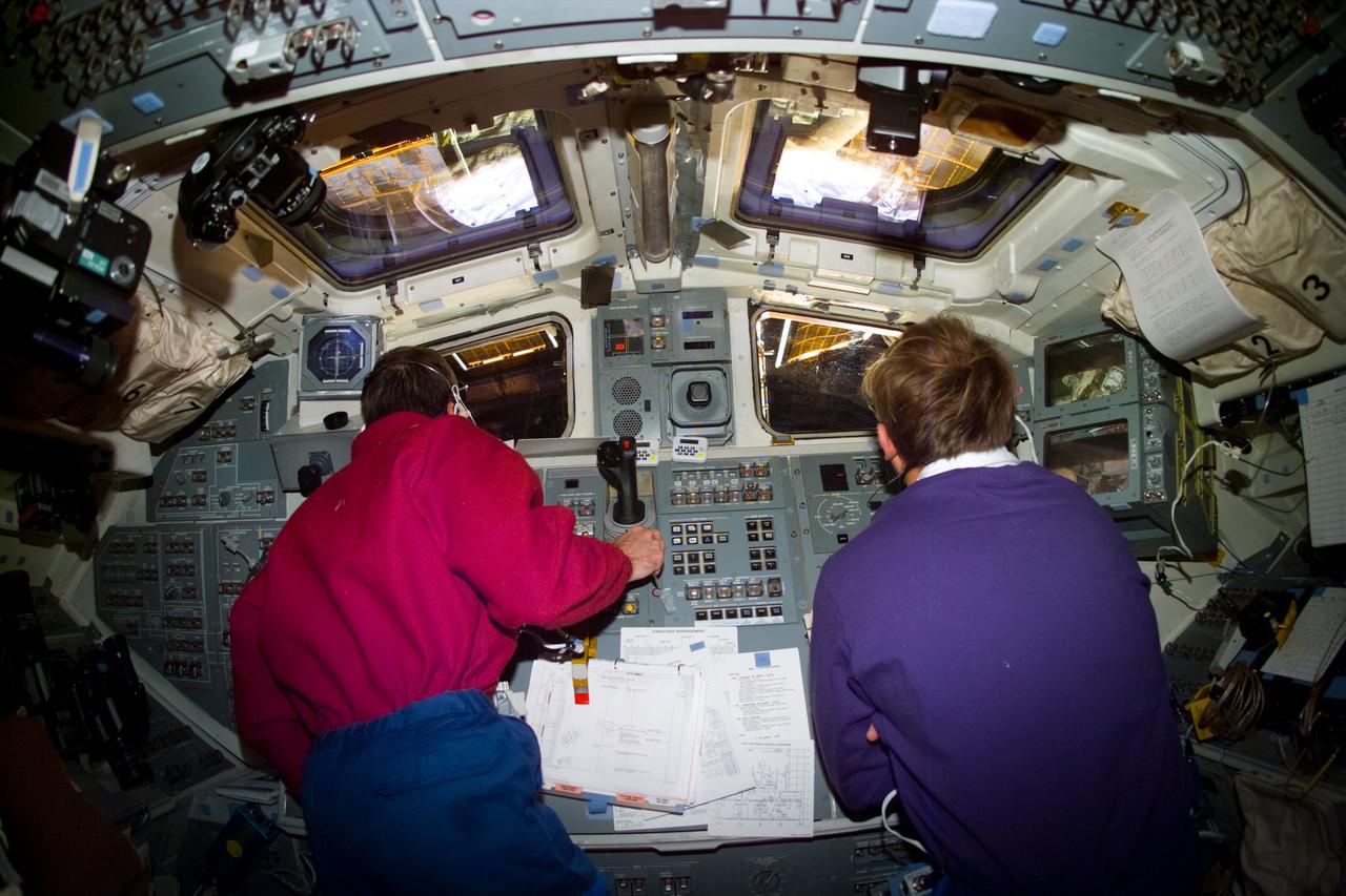 S82-E-5644 (17 Feb. 1997) --- Inside the Space Shuttle Discovery's cabin, astronauts Scott J. Horowitz (left), STS-82 pilot, and Mark C. Lee, payload commander, monitor the mission's fourth Extravehicular Activity (EVA) to service Hubble Space Telescope (HST). This view was taken with an Electronic Still Camera (ESC).