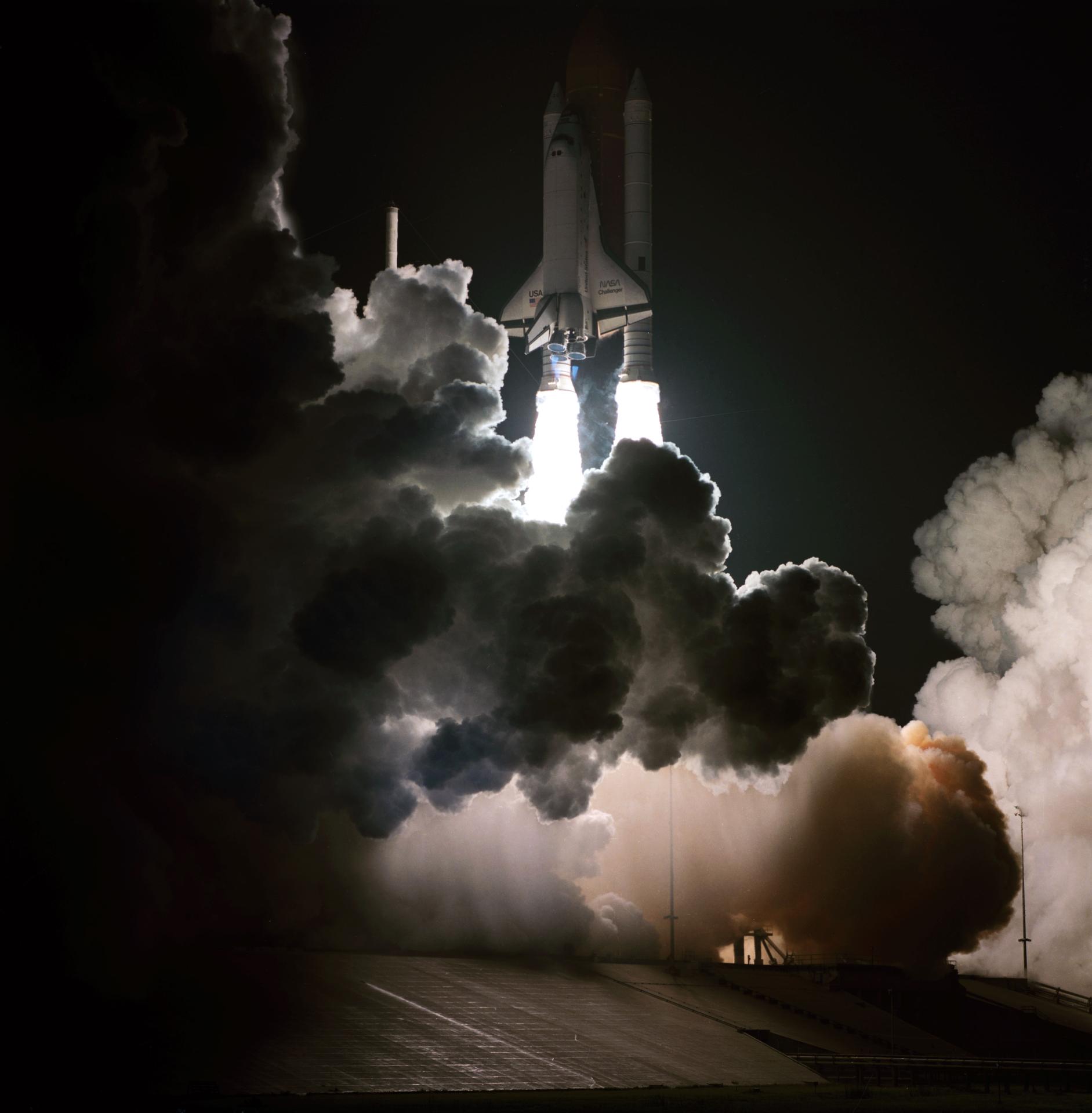 STS-8 lifts off from the launch pad at Kennedy Space Center at night.
