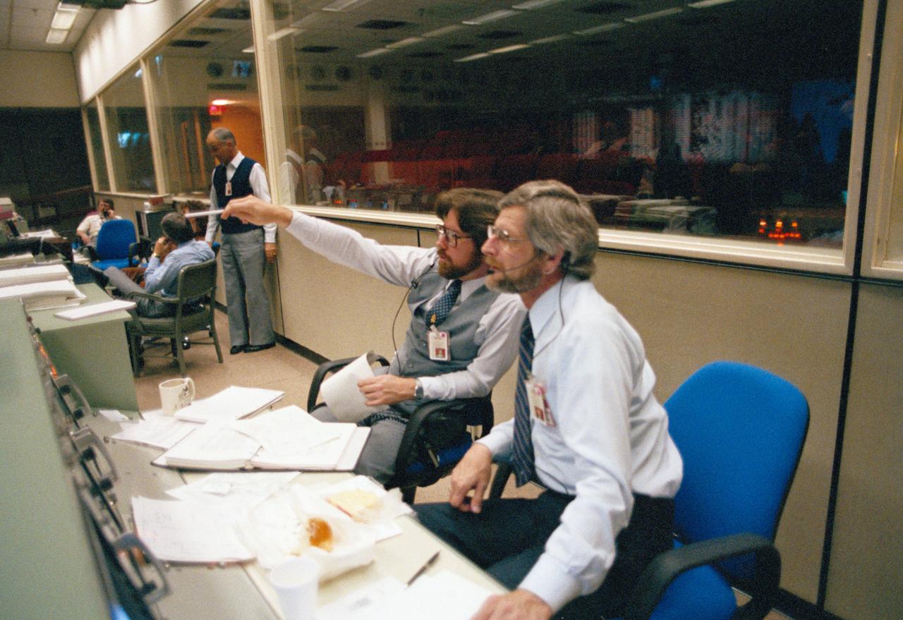 s83-46015 Views of the Mission Control Center activity of Eidophor with STS-9 Landing Data; PAO Console ith Steve Nesbitt and Harold S. Stall; FD Console with Charles Lewis and Ralph Hoodless, Lewis and M.P. "Pete" Frank; and the hanging of the STS-9 Plaque