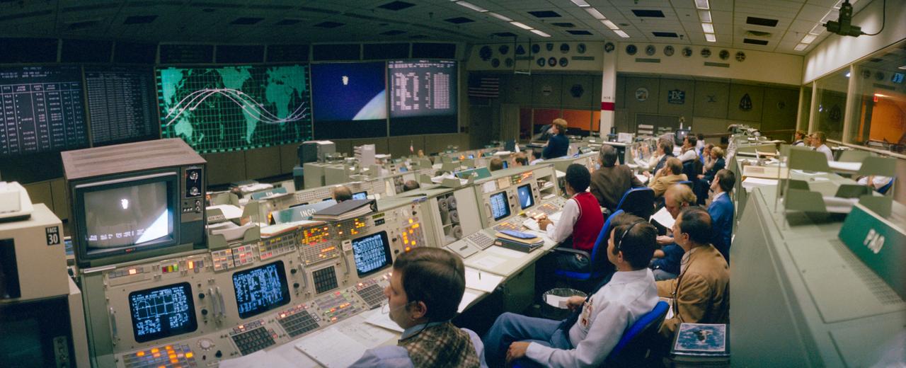 S84-26503 (7 Feb 1984) ---  This wide angle, overall view of activity in the mission operations control room in the Johnson Space Center?s mission control center, was photographed during the first even non-tethered extravehicular activity (EVA) in space.  The large MOCR monitor and those at individual consoles feed to ground controllers the spectacular scene of Astronaut Bruce McCandless II ?suspended? I space above the blue and white Earth.  The scene was photographed at 7:30 a.m. (CST), February 7, 1984.