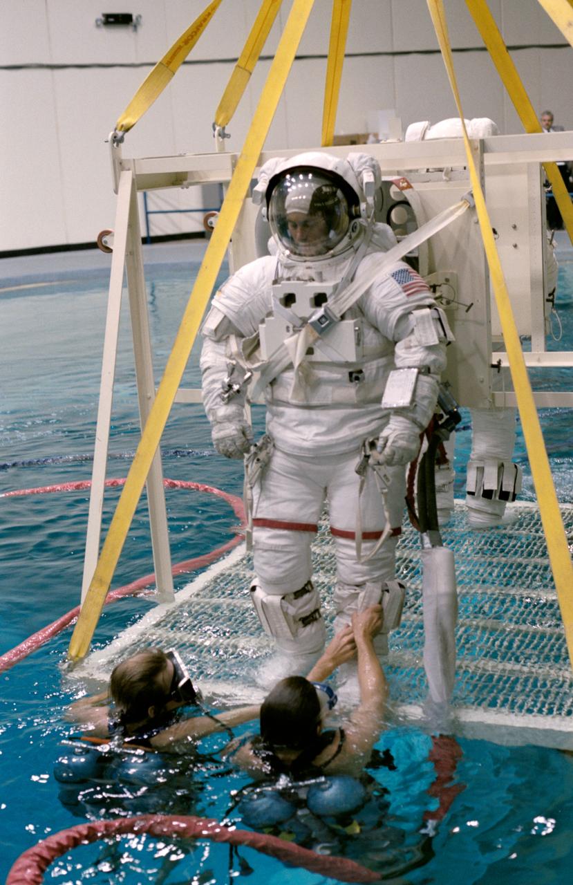 S84-28204 (26 Feb 1984) --- Astronaut Richard M. (Mike) Mullane, one of three 41-D mission specialists, is almost ready for submerging in the 25 ft. deep facility used to simulate space tasks on earth. Moments later, the 41-D crewmember was floating around a submerged Shuttle mockup simulating a contignency EVA for his seven-day flight.  Partially pictured in the background is Astronaut Steven A. Hawley, who would share EVA duties with Mullane in the event an EVA was deemed necessary.  All Shuttle crews, many of which are not scheduled for definite EVAs, possess team members trained to perform in space certain tasks normally done remotely in the event of systems failures.  Among those contingent tasks is the manual closing of the  Shuttle's cargo bay doors.  This photograph was taken by Otis Imboden.
